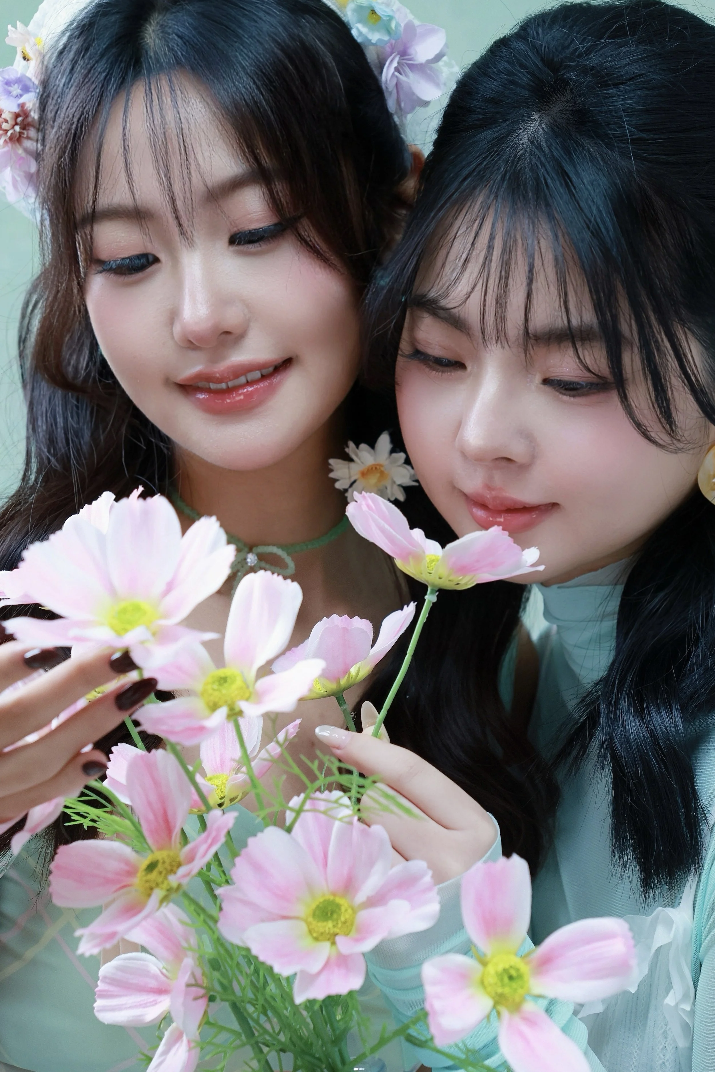 Two female friends in mint green outfit posing with pink flowers