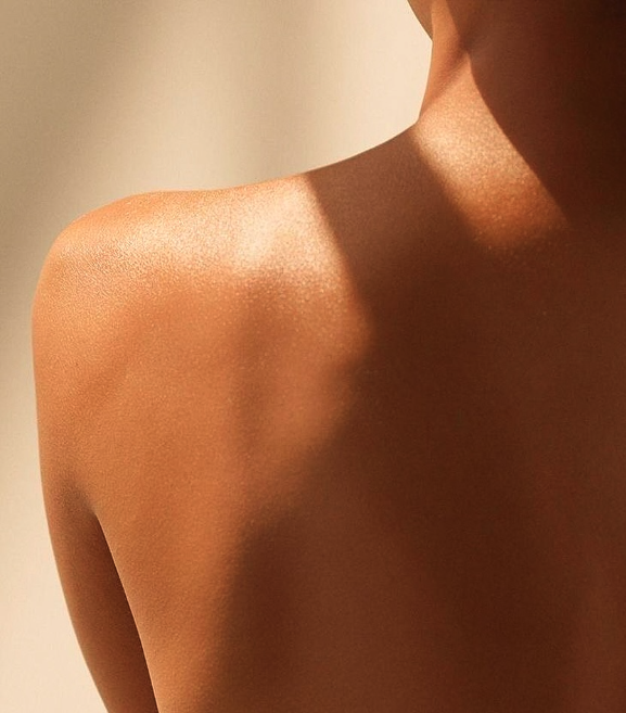 Close-up of a person's shoulder and upper chest with warm lighting.