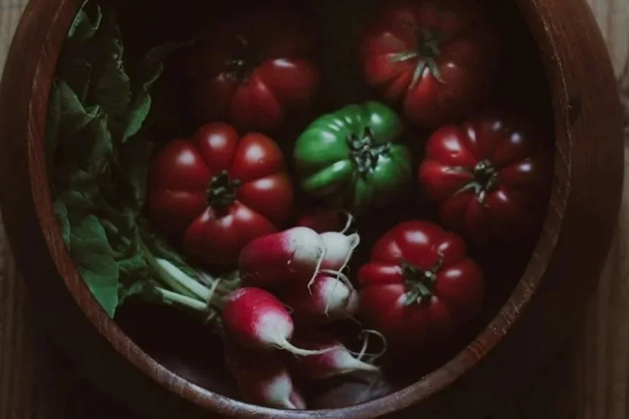 Three images of fresh tomatoes and radishes with green leaves. The first image shows cherry tomatoes on the vine in a white dish. The second image displays heirloom tomatoes and radishes in a wooden bowl. The third image features what appears to be h
