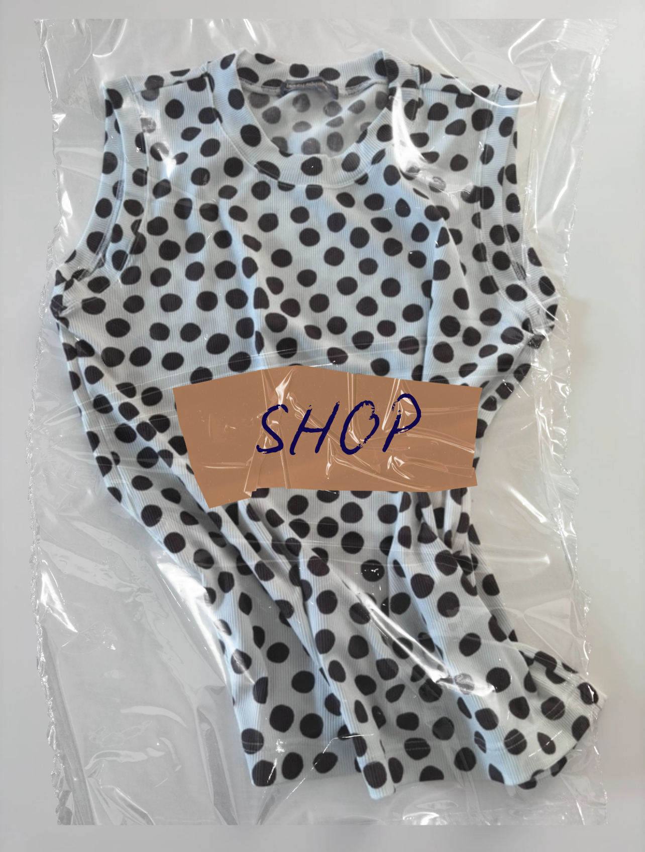 Vêtements en plastique avec un t-shirt à pois noirs et blancs et un symbole 'SHOP' écrit sur une étiquette