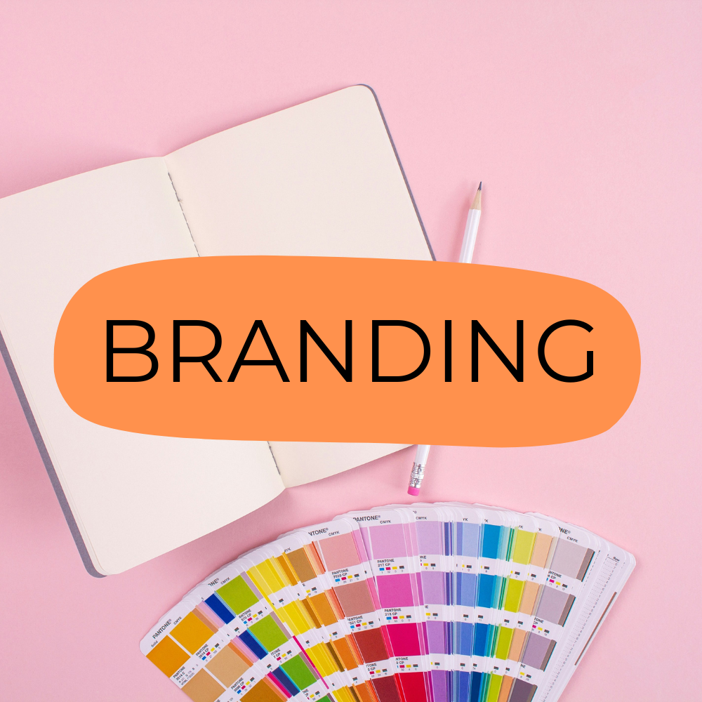 An image from services of De Nada Creating Studio: Branding. An open notebook, a pencil, and a Pantone color guide fan deck on a pink background to show how we start from a blank page to create a new world.