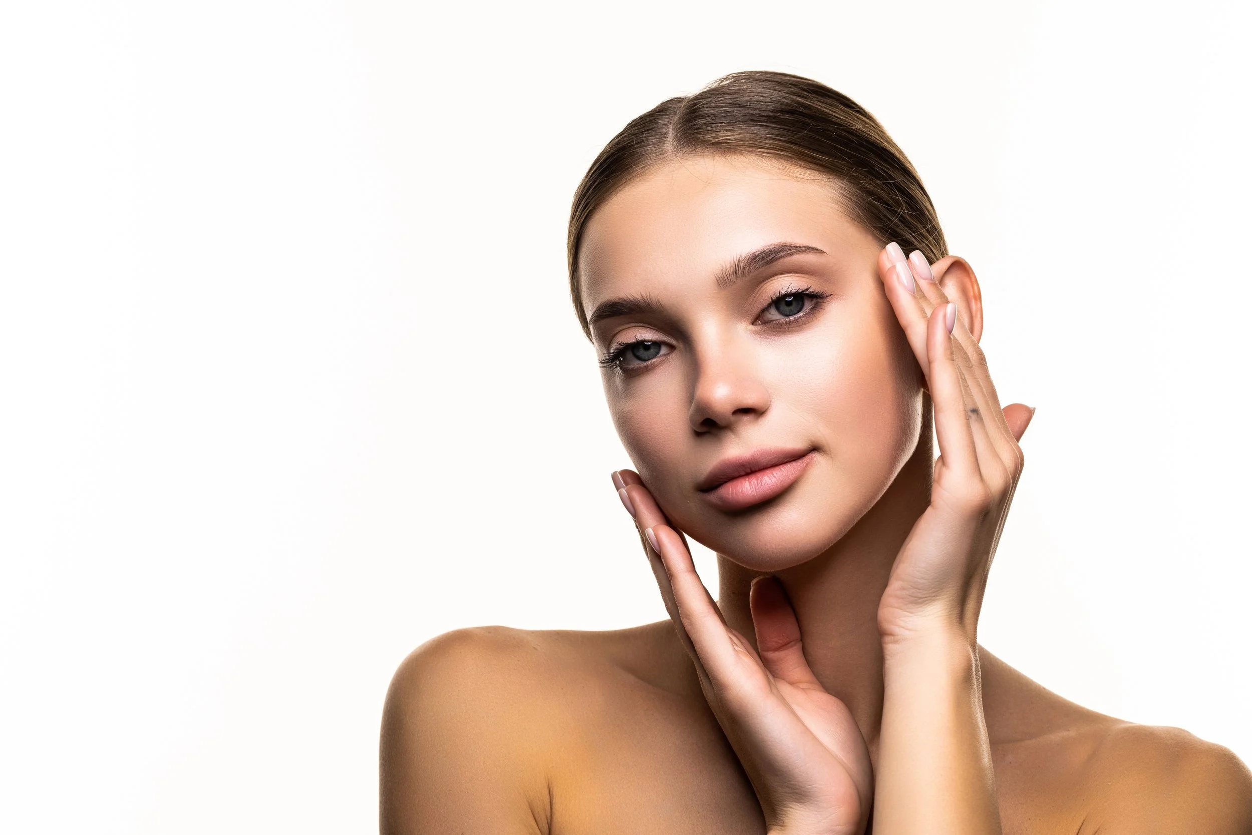 Female model with smooth, radiant skin holding her face, representing dermal filler results.
