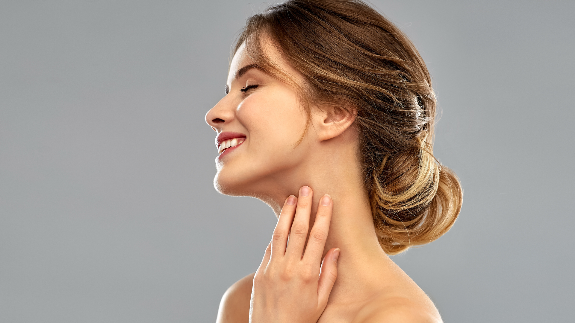 Female model smiling and looking off to the side with a lifted, elongated neckline representing XERF skin tightening results.