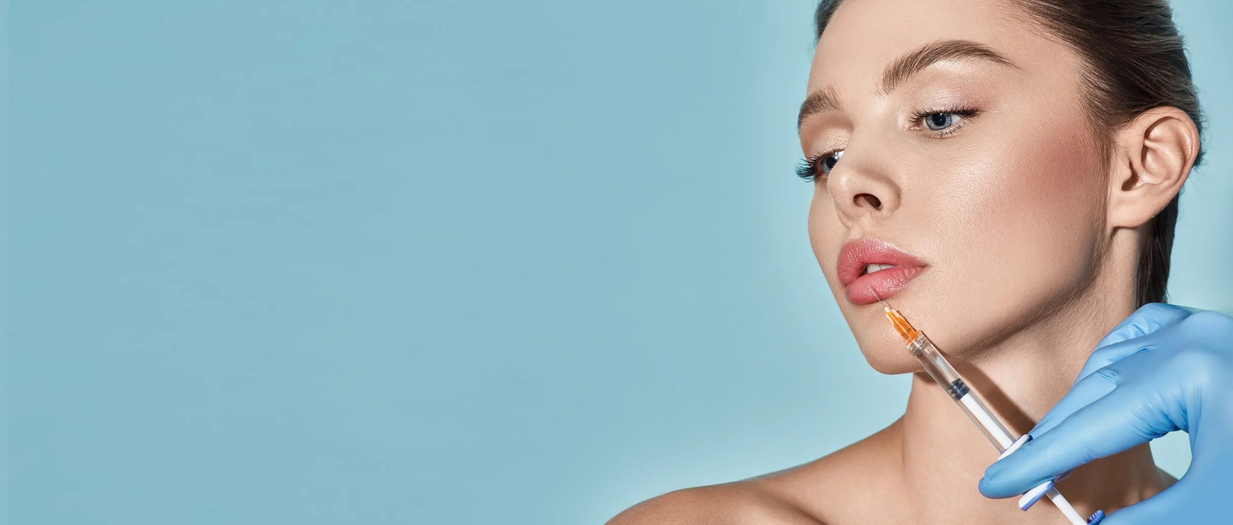 Female model receiving precise lip filler injection administered by a professional with gloved hands.
