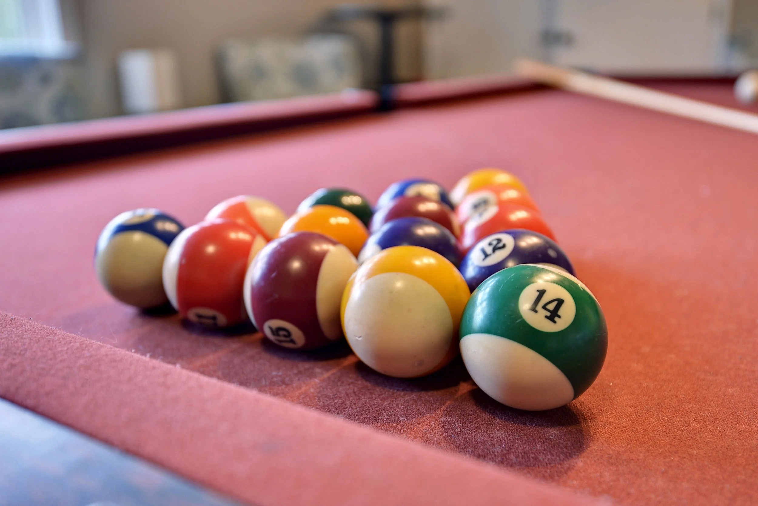 Pool balls arranged triangular rack on a red pool table.