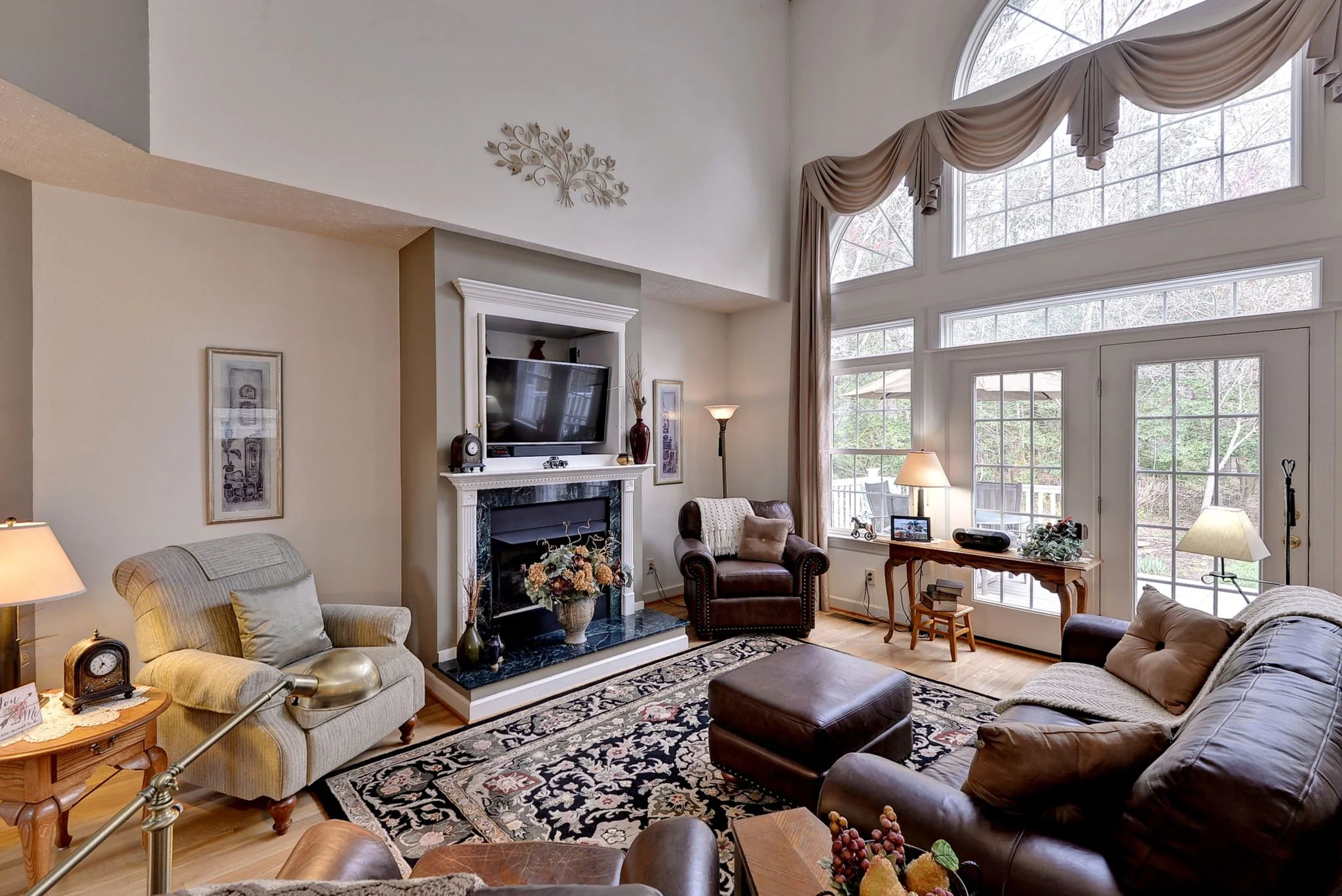 Living room with large windows, beige and brown furniture, a fireplace, and decorative items.