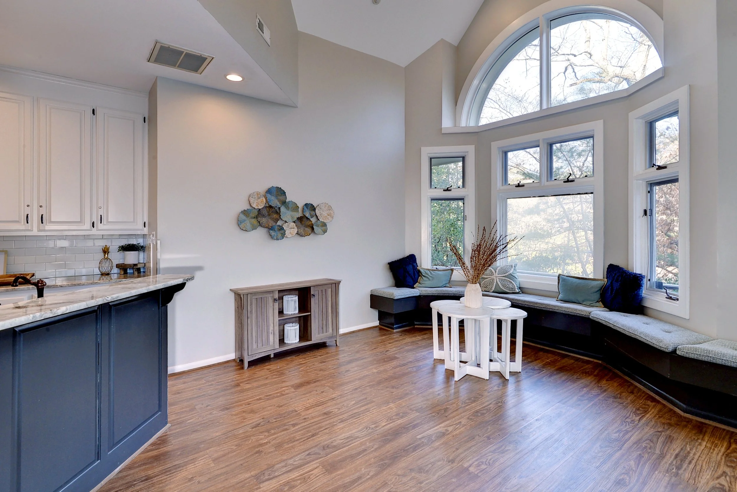 Living room with large bay window, built-in seating, white and blue decor, and hardwood floors.