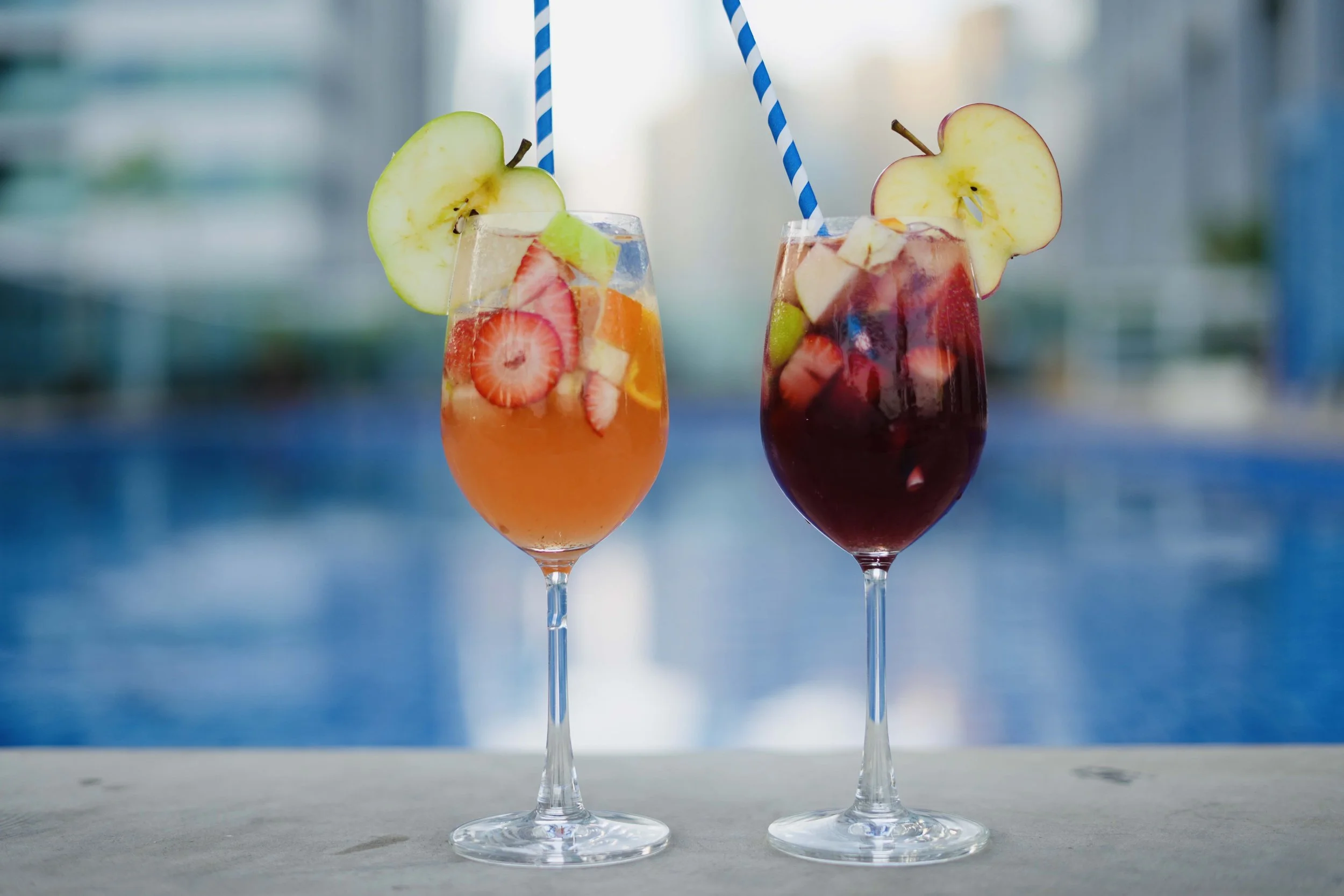 Two glasses of Sangria next to a pool.