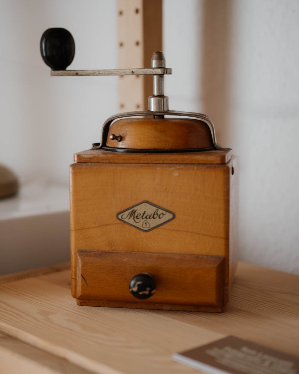 Vintage Kaffeemühle aus Holz mit Metallgriff und Logo 'Metabo' auf der Vorderseite.