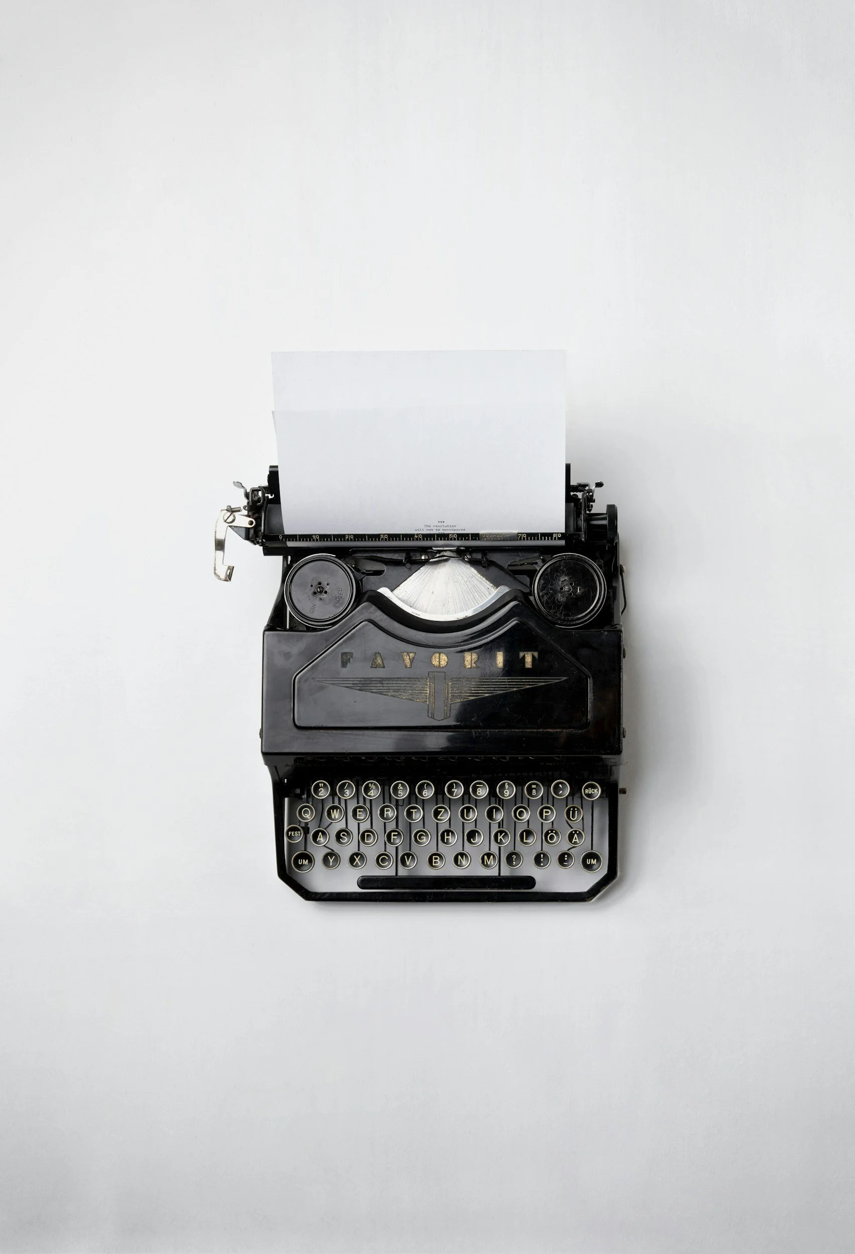 Black vintage typewriter with white paper in a blank space.