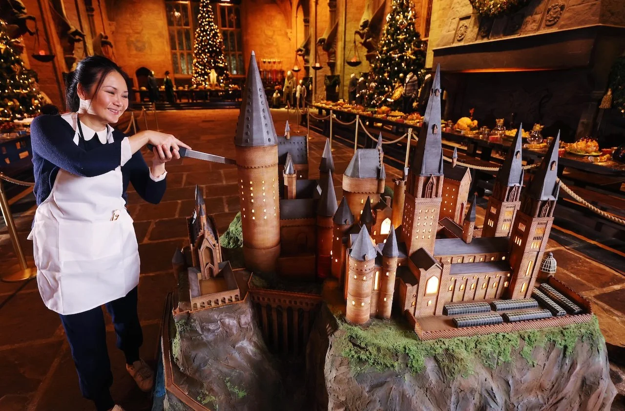 Artist Michelle Wibowo ceremoniously cutting into the massive Hogwarts Castle cake.
