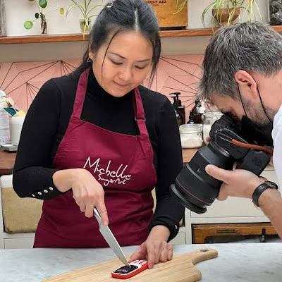 Michelle Wibowo is preparing to cut the cake with a cameraman ready to capture