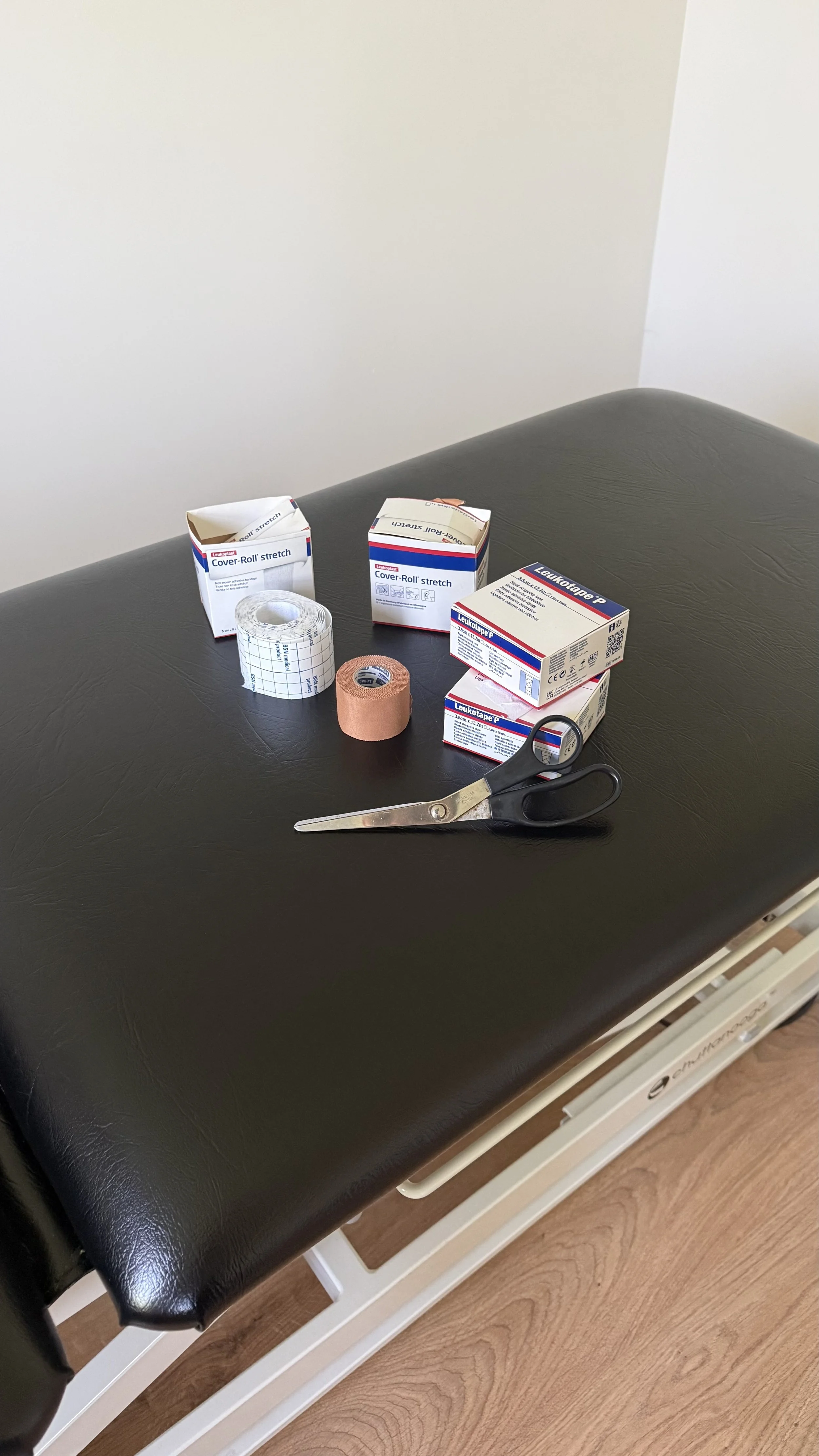 Medical examination table with medical tape, scissors, and bandages on top.
