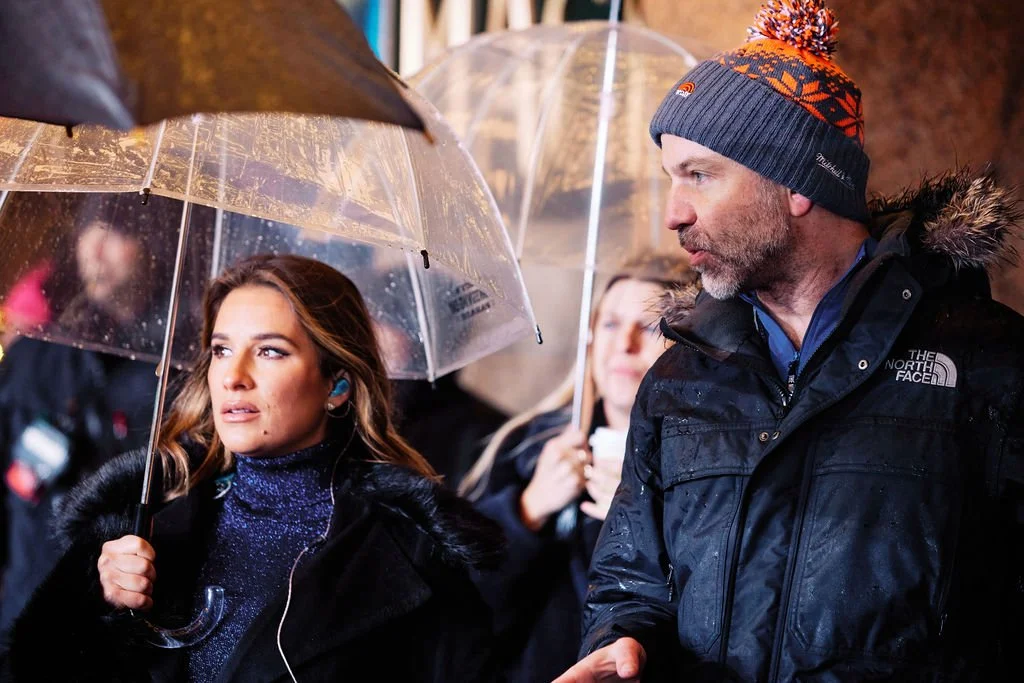 People with umbrellas in rainy weather, wearing warm clothing.