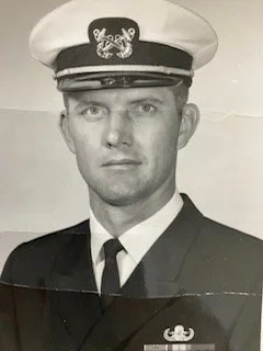 Black and white photo of a man in a military uniform with a peaked cap, facing forward.