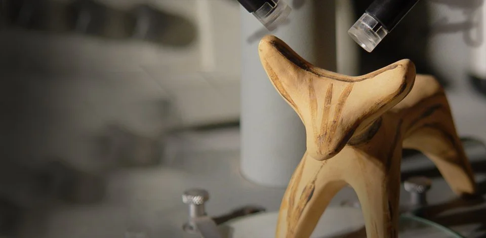 A wooden sculpture resembling a dog in front of a microscope, in a laboratory setting.