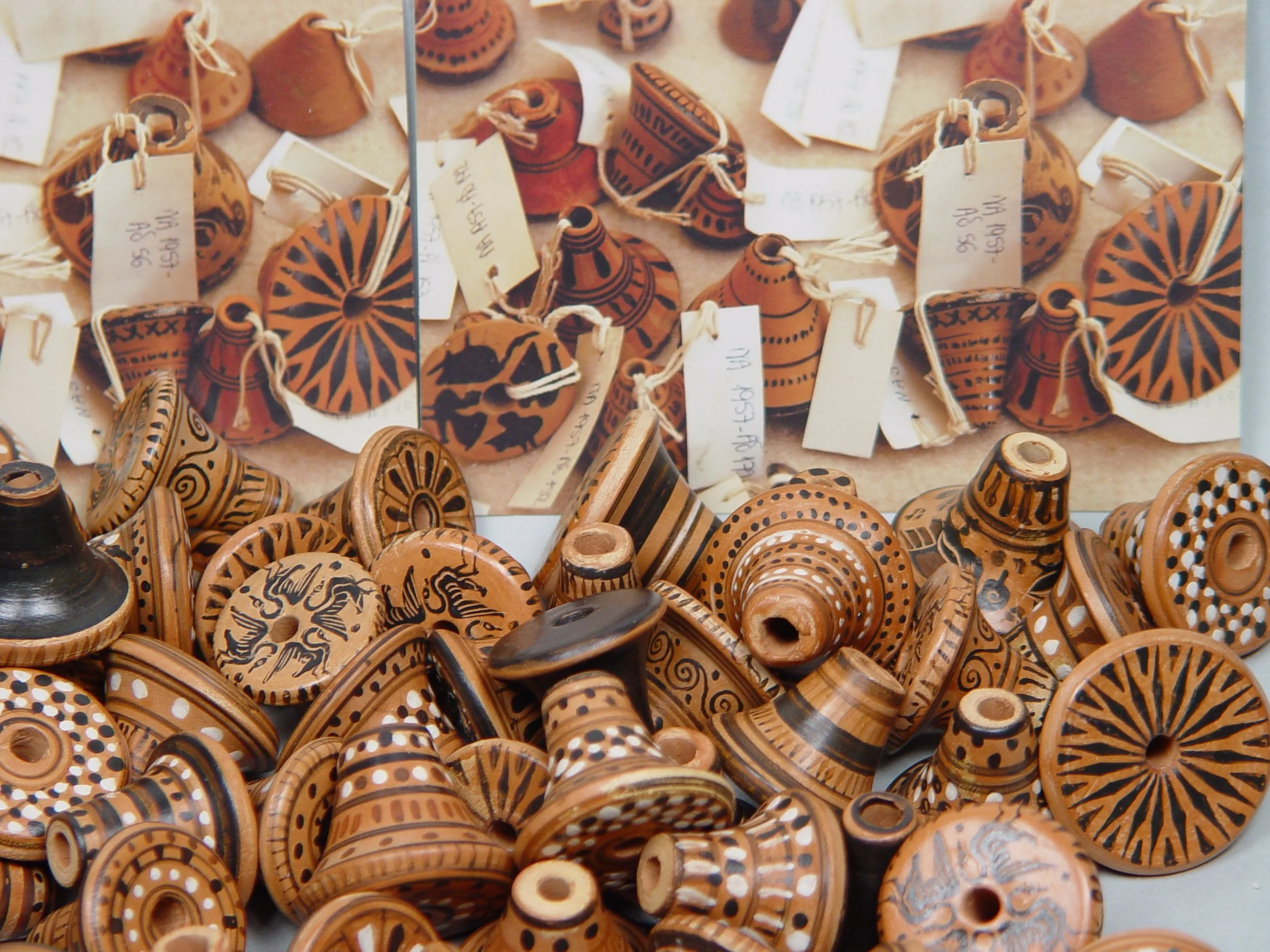 Various traditional handcrafted clay pottery pieces with black painted geometric and abstract patterns, some with tags attached.