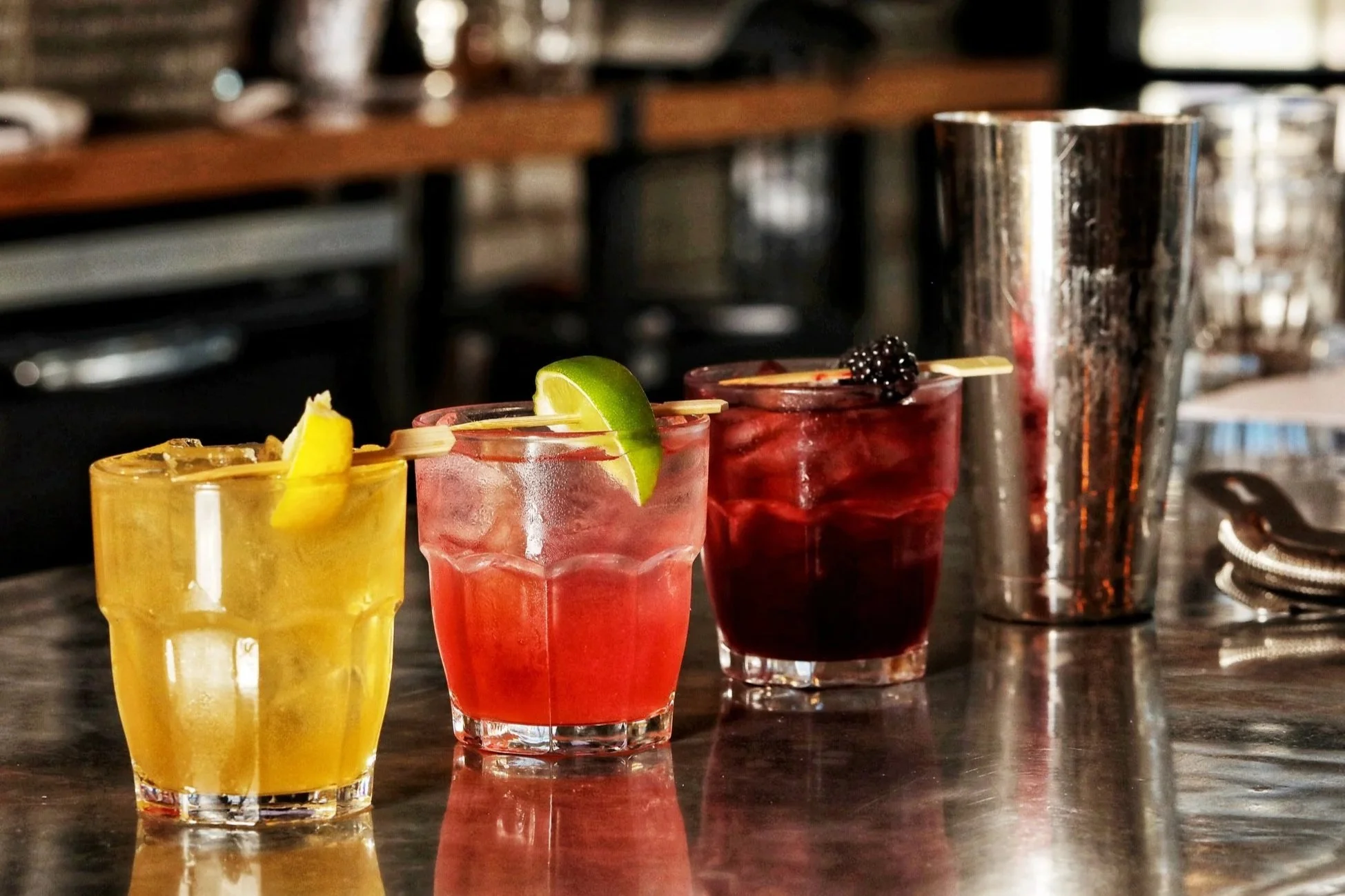 Glass of red sangria with orange and lime slices on a wooden table next to a white and blue napkin.