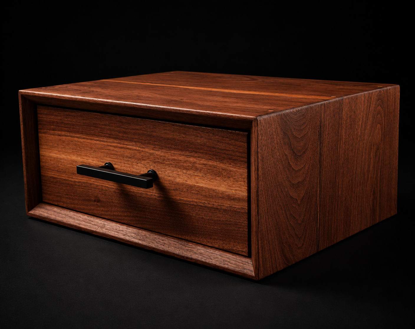 A wooden storage box with a single drawer and a black handle, made of dark, rich wood, set against a black background.