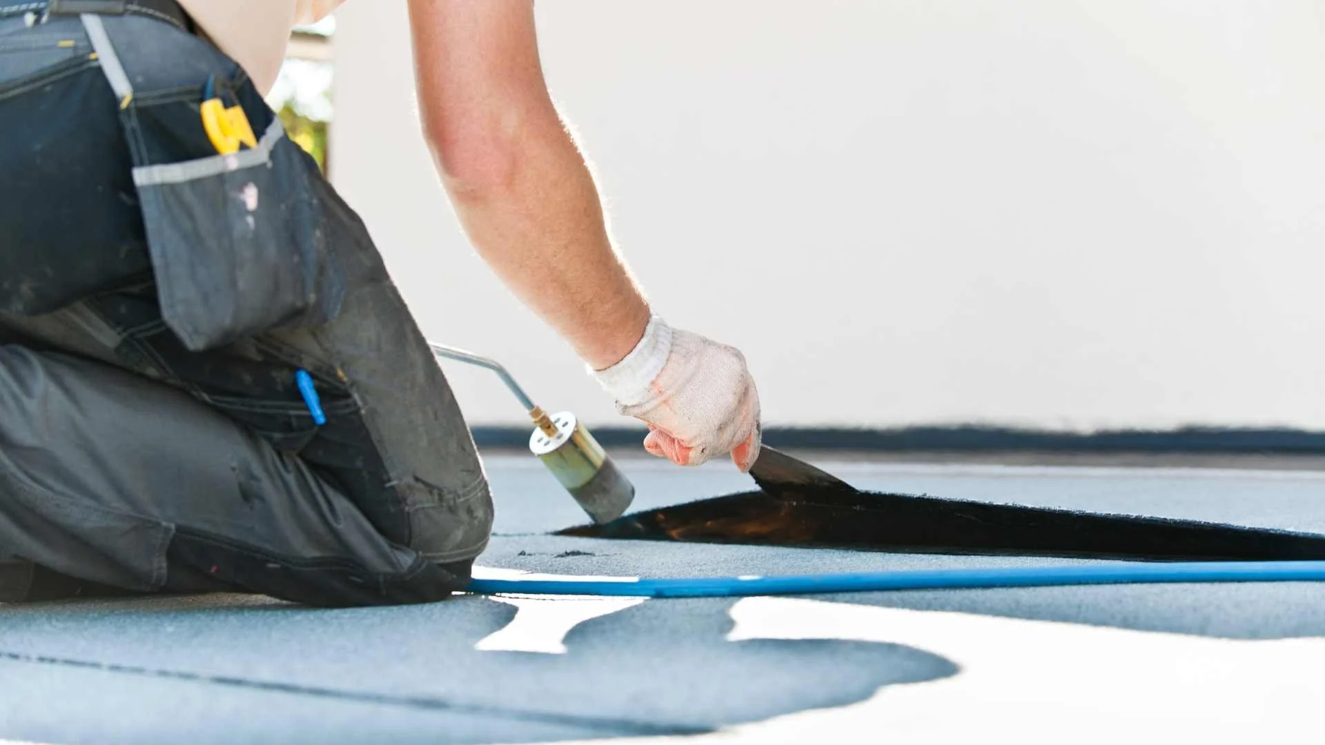 a roofer using a blowtorch on a commercial roof