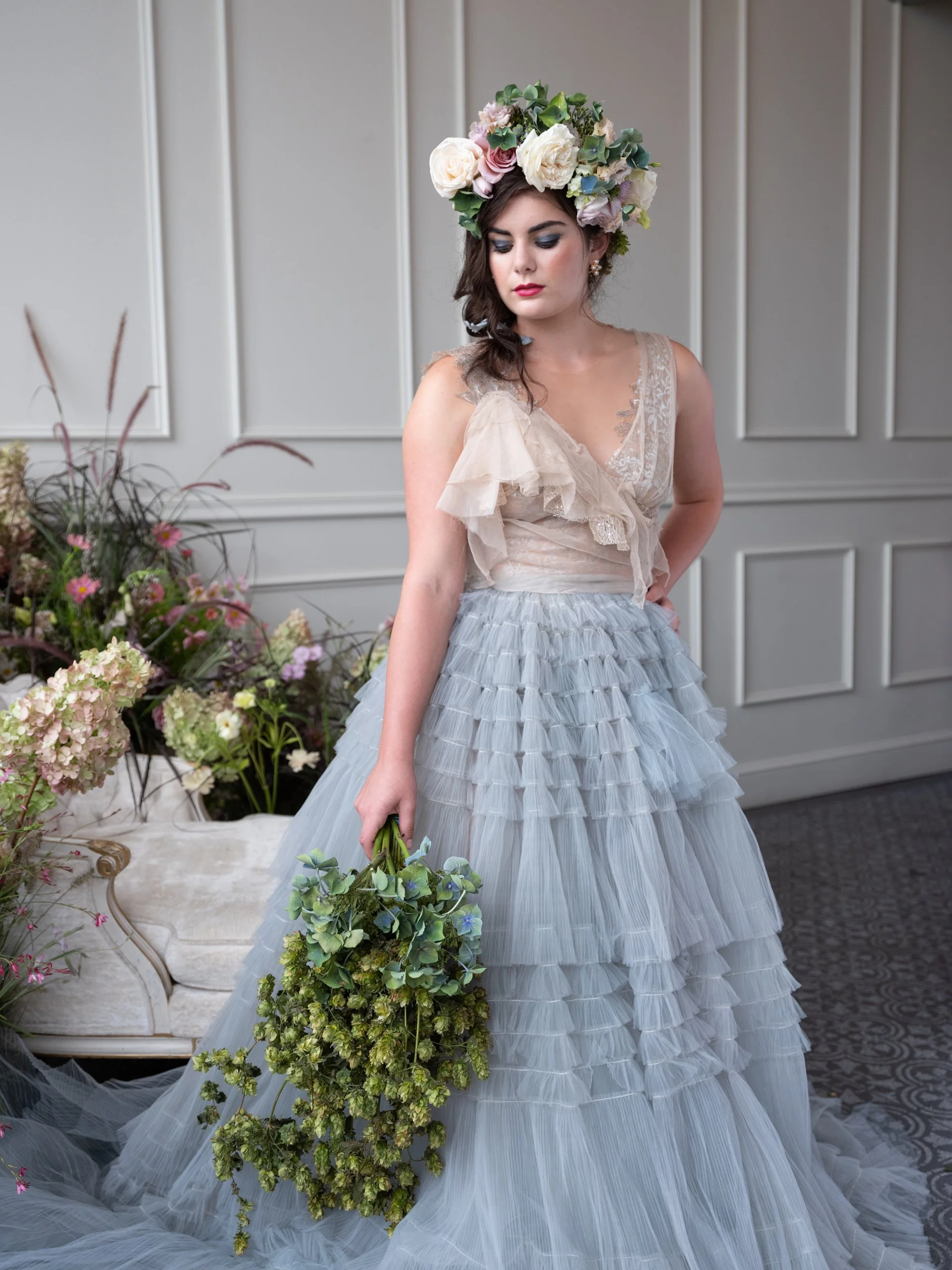 A romantic fashion moment from a styled shoot in Portland, Oregon, showcasing a Claire La Faye blue tulle gown and a statement floral crown of roses and hydrangea.