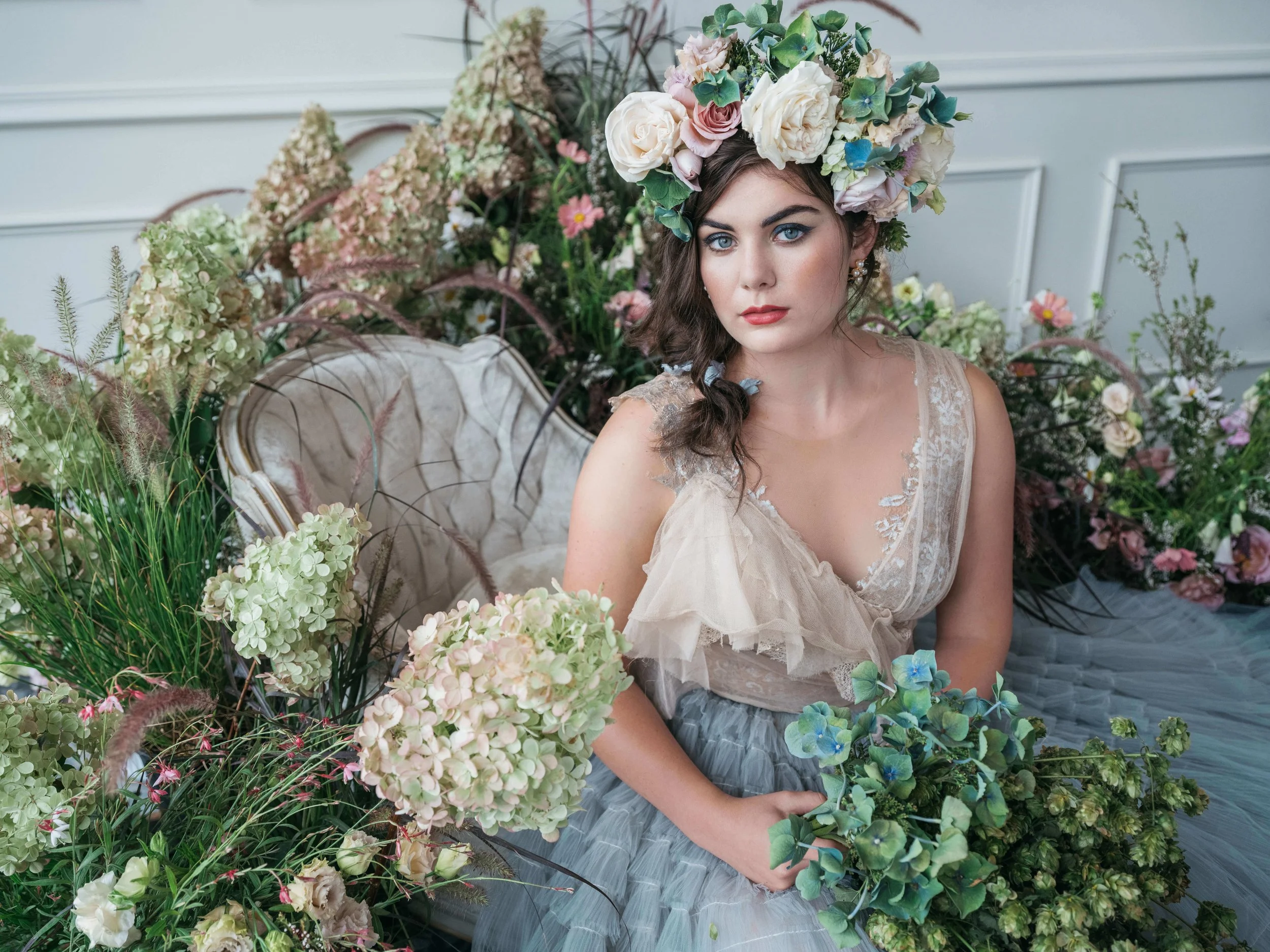 Floral editorial scene with antique chair and lush garden-inspired arrangements in soft neutrals and greenery, captured during a styled shoot in Portland.