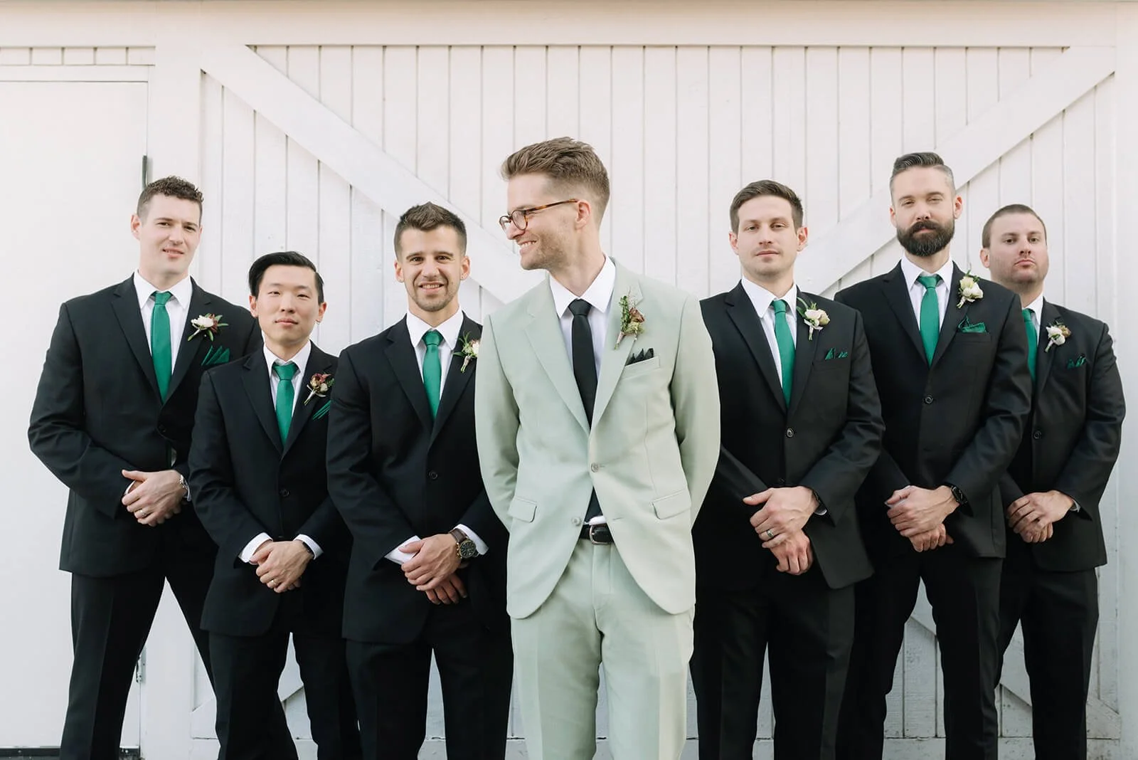 A modern fall wedding at The Evergreen featuring rich green suits and autumn-toned boutonnieres for the groomsmen.