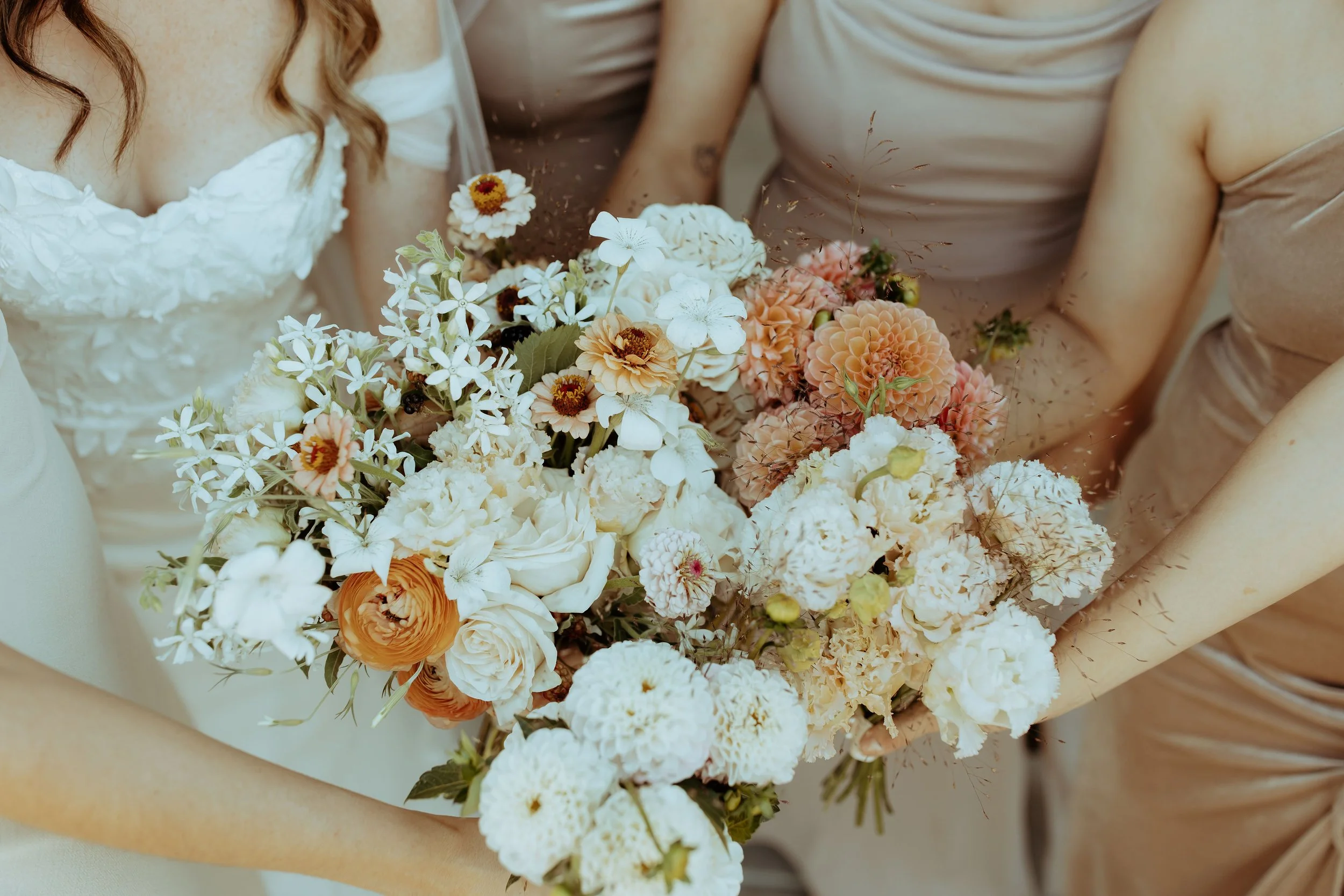 Close-up of the bride’s bouquet, featuring blush dahlias, white agrostemma, caramel-colored zinnias, and Oregon-grown garden roses.