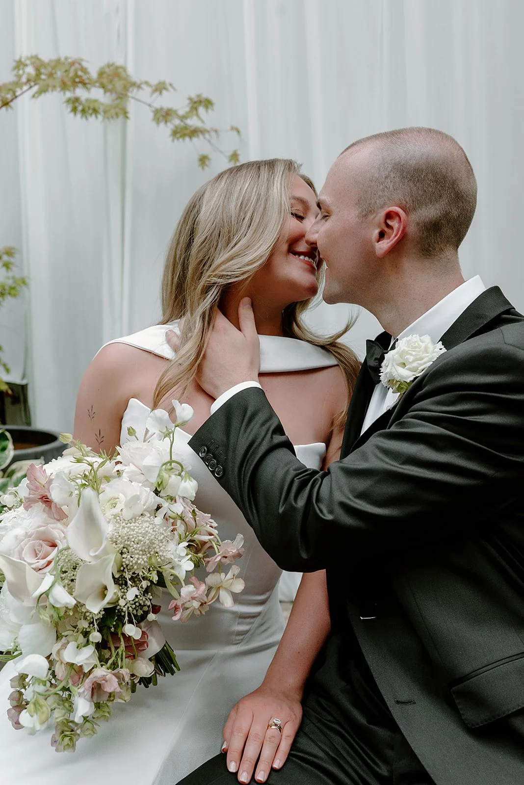 Romantic wedding portrait featuring a lush, sustainable bridal bouquet of local blooms, including calla lilies, agrostemma, butterfly ranunculus, hydrangea, and garden roses. Designed by Portland florist Roots of Joy for a modern backyard celebration