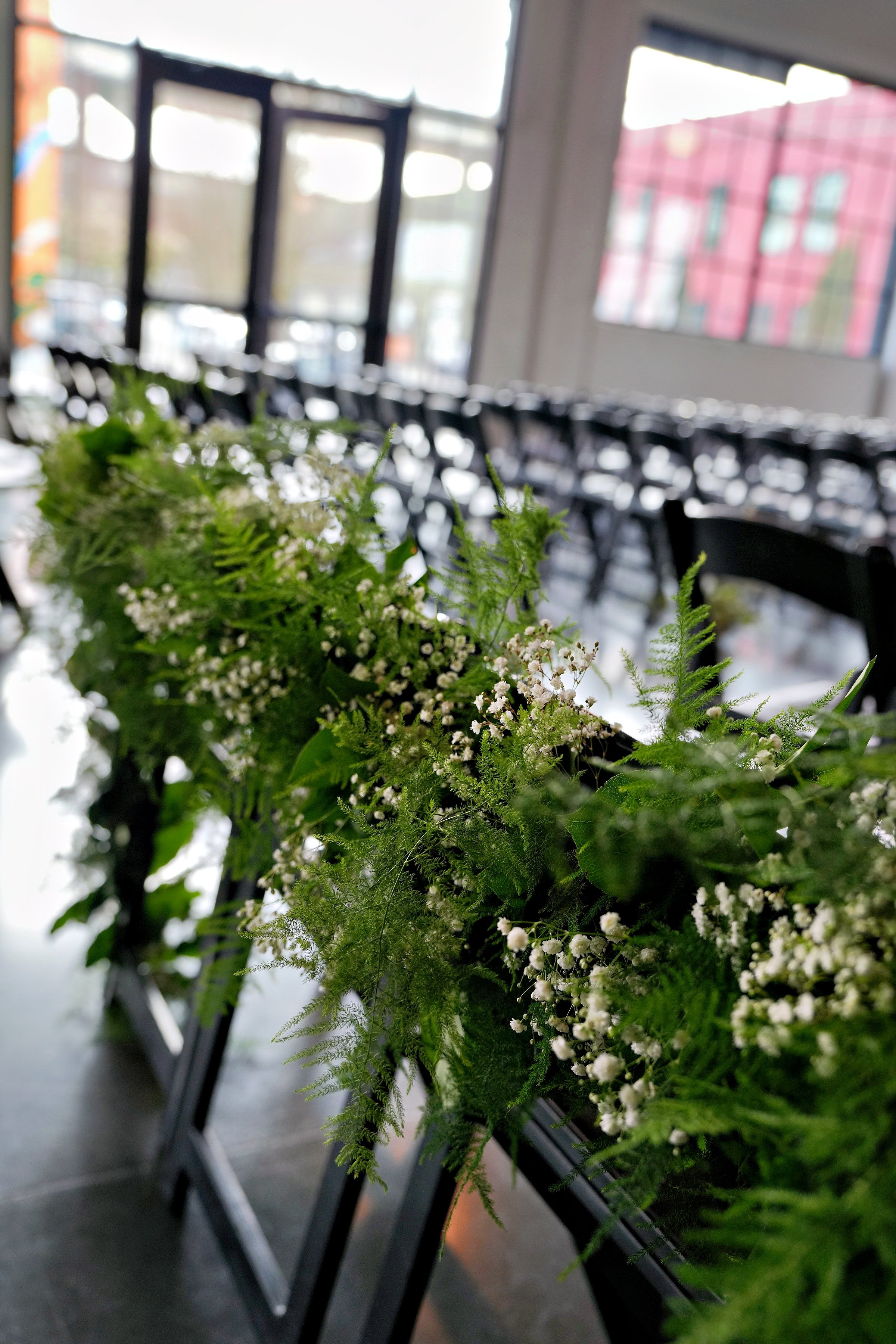 Lush chair-back installations made from fern, baby’s breath, and delicate greens created a living aisle for the ceremony.
