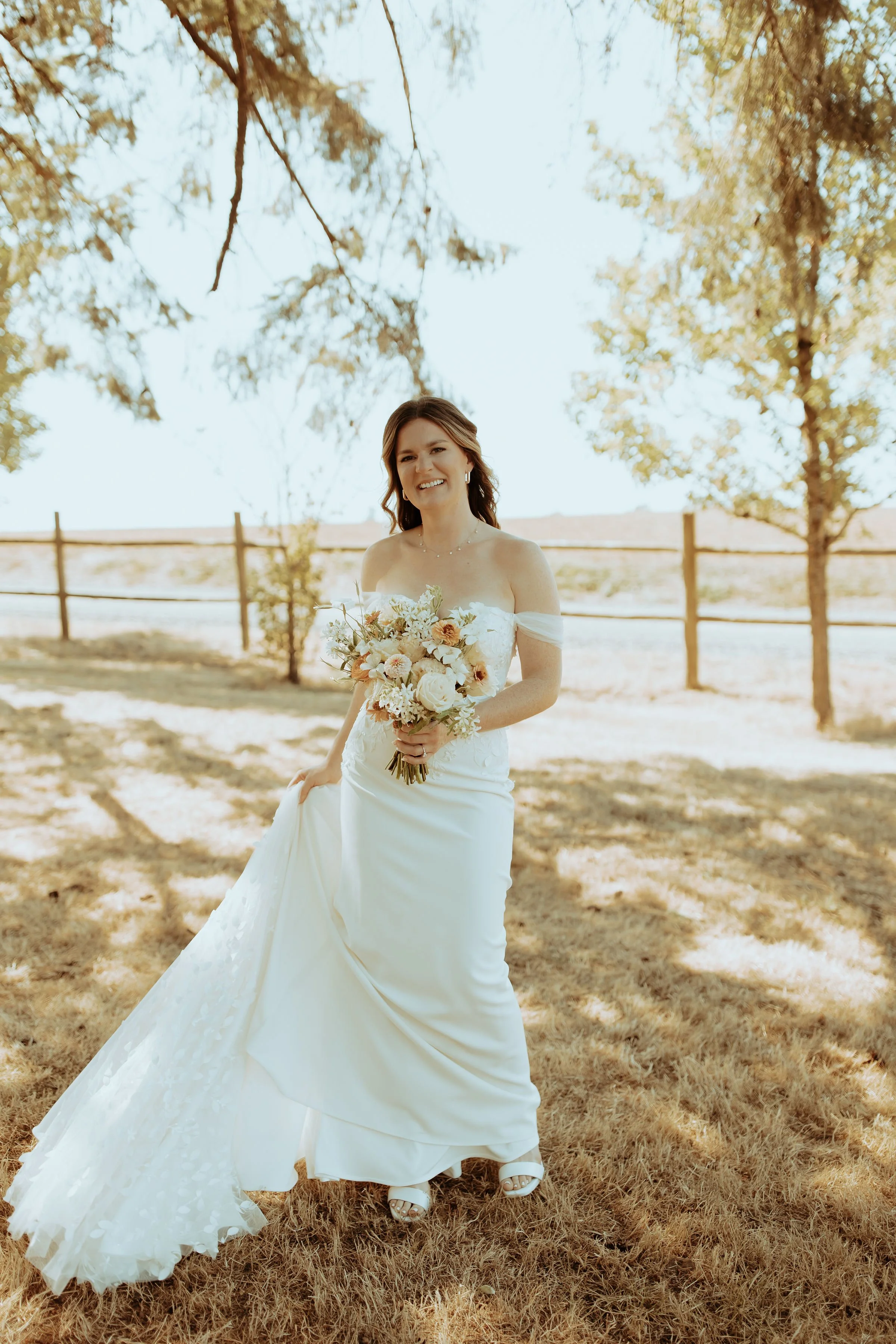 Bride holding a romantic summer bouquet with white garden roses, blush zinnias, and terracotta ranunculus at Abbey Road Farm, Oregon.