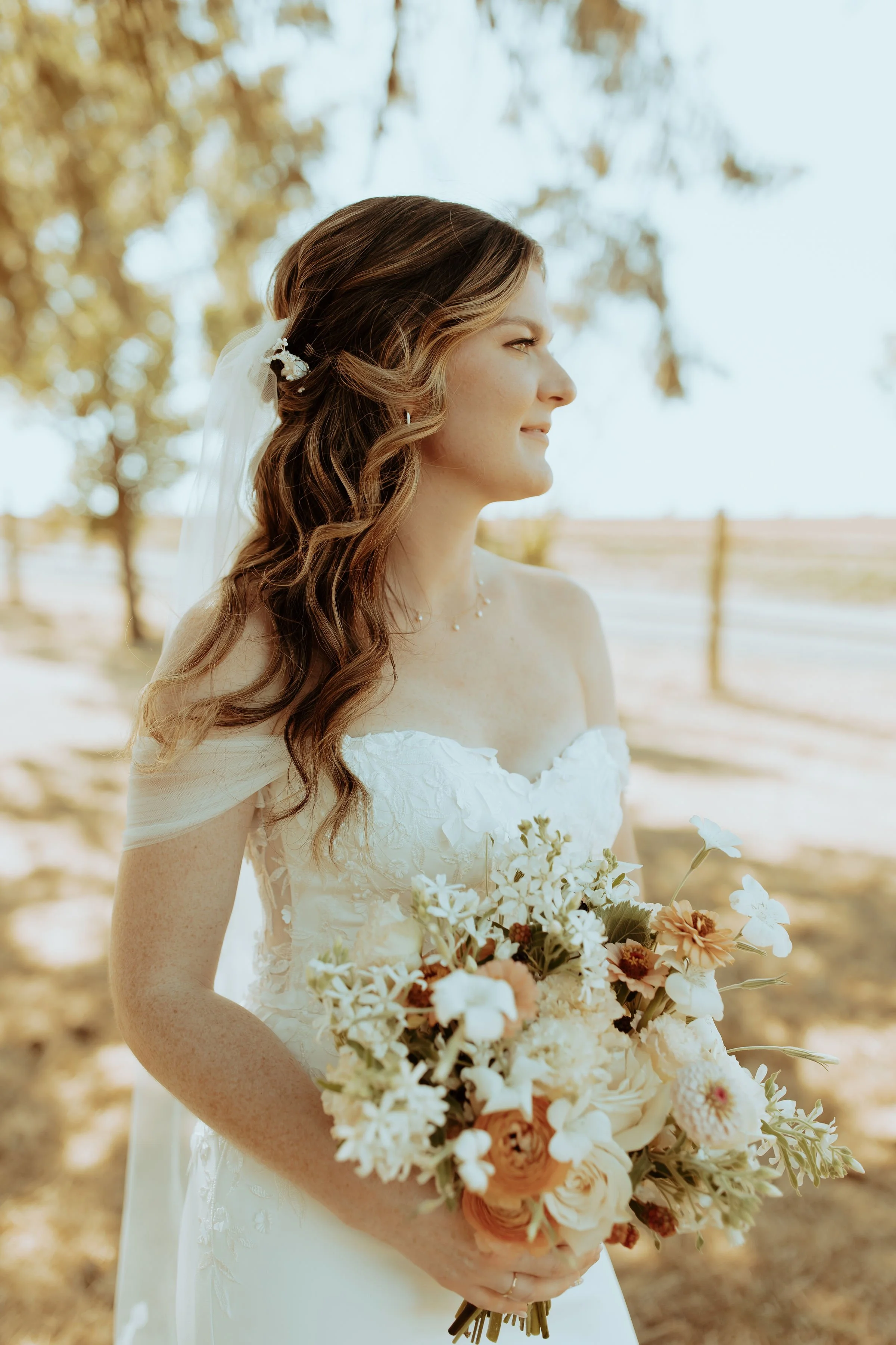 Bride in off-the-shoulder gown and embroidered veil, holding late summer wedding bouquet with Oregon-grown blooms.