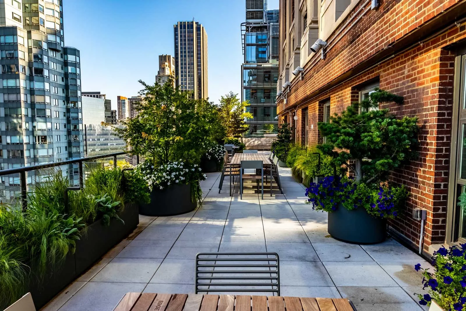 Manhattan rooftop terrace with brick wall, planters, and city views