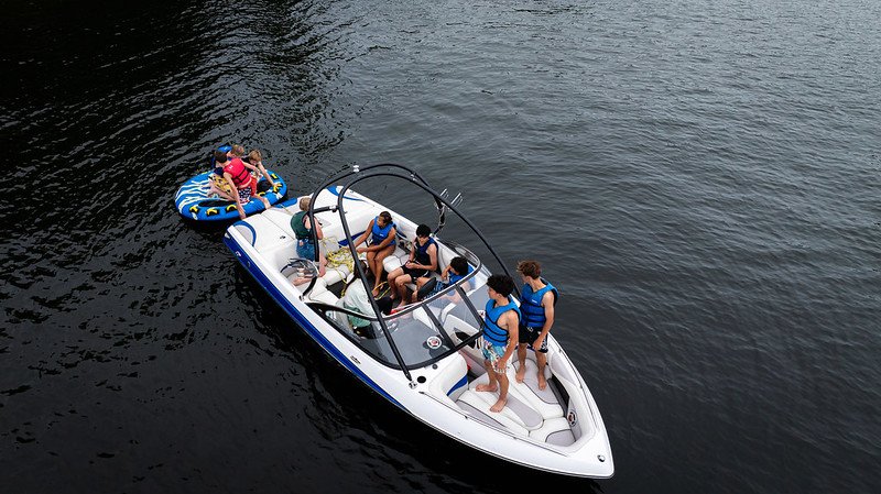 Aerial view of people in life jackets on a motorboat and an inflatable tube on a lake.