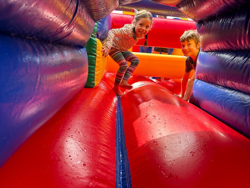 Two kids playing inside a colorful inflatable bouncy castle.