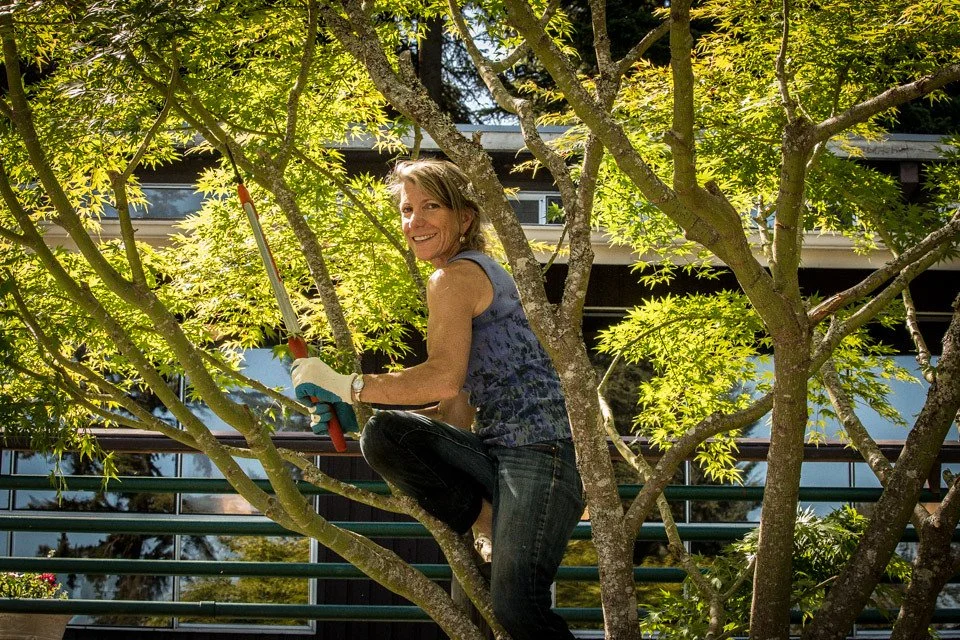 Woman smiling while trimming tree branches.
