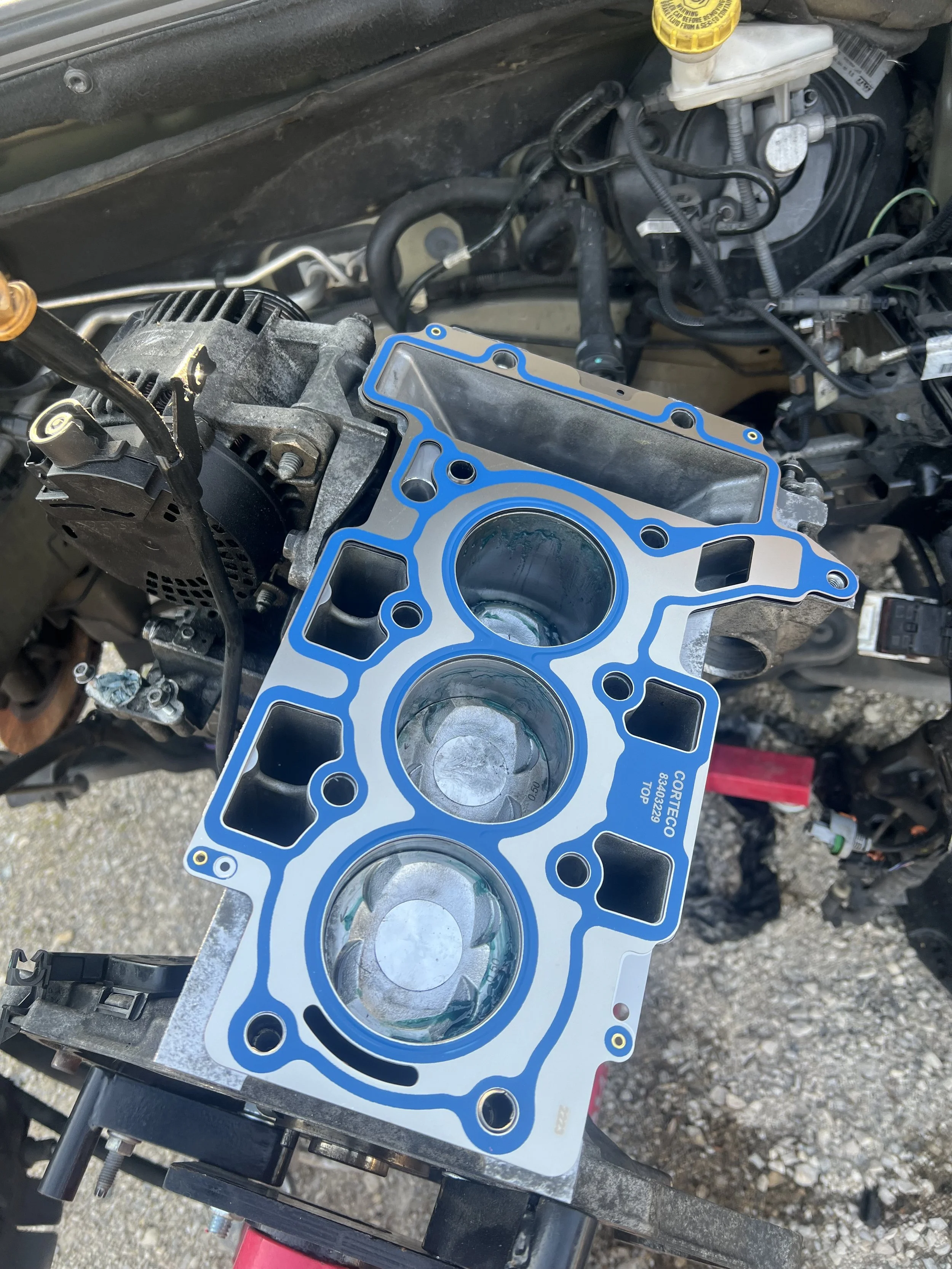 Moteur de voiture avec une culasse déposée, visible le bloc de cylindres et les pistons.