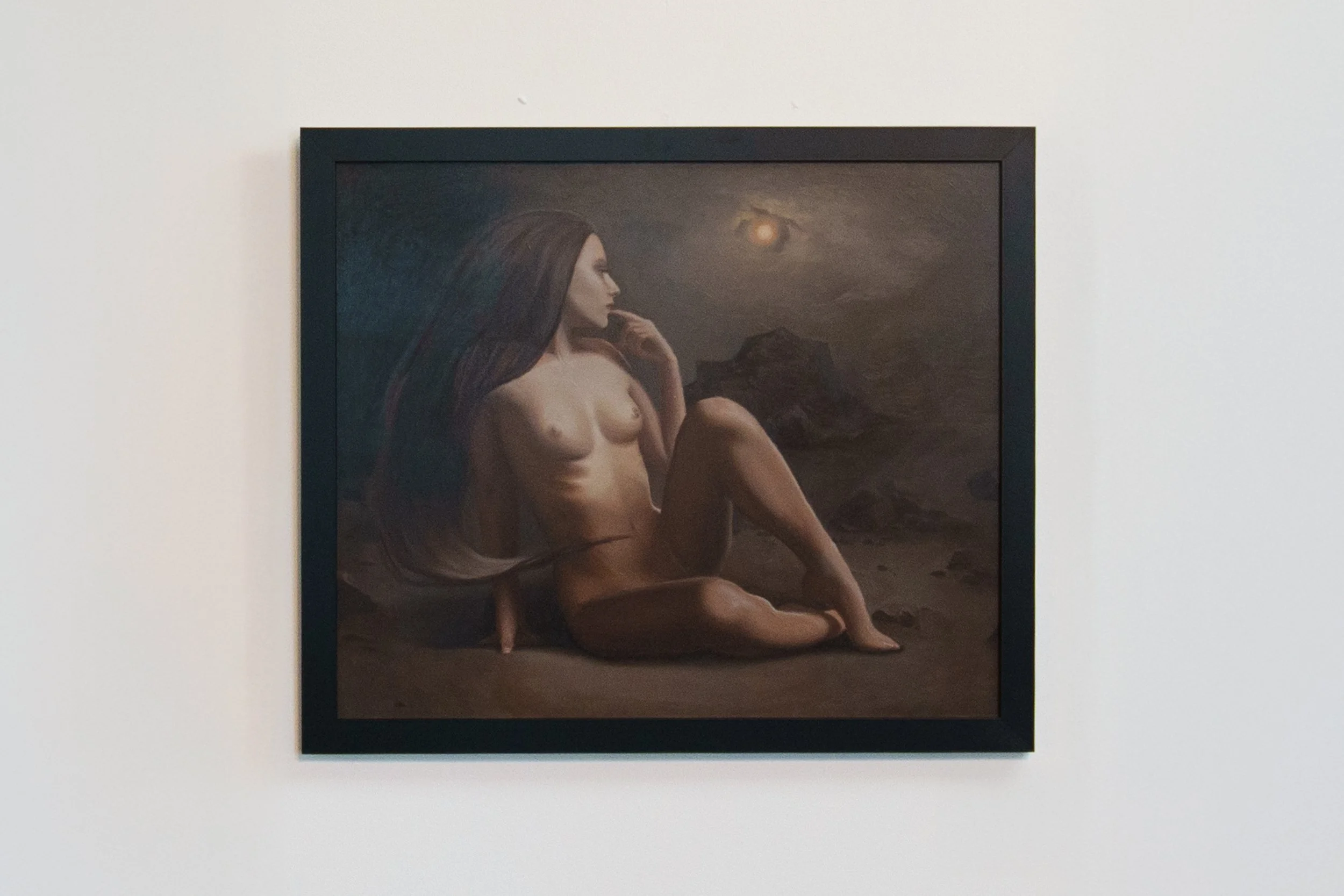 Painting of a naked woman with long hair sitting on the ground under a moonlit night sky with mountains in the background.