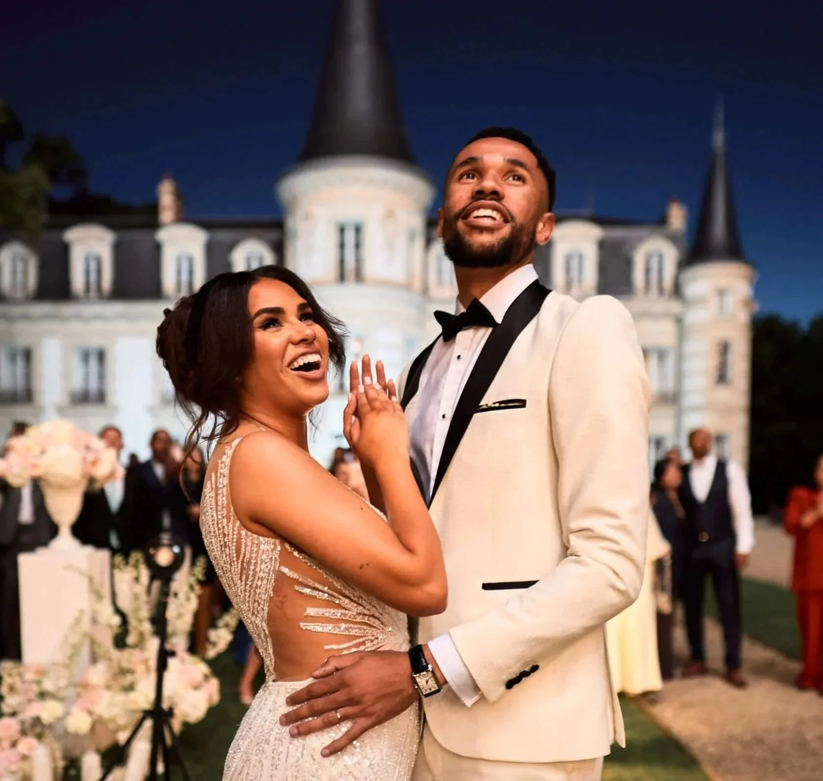une photo d'un couple face à un château.