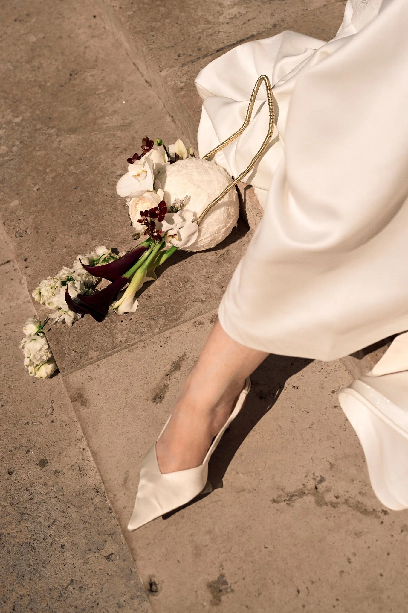 Détail sur un bouquet de fleurs originales et la robe et chaussures de la mariée