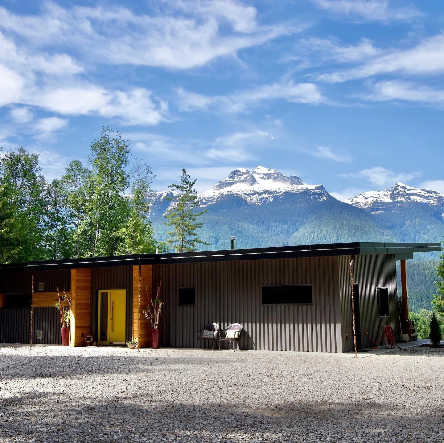 modern house with black roof sidingin front of a breathtaking mountain landscape and a blue sky with light clouds