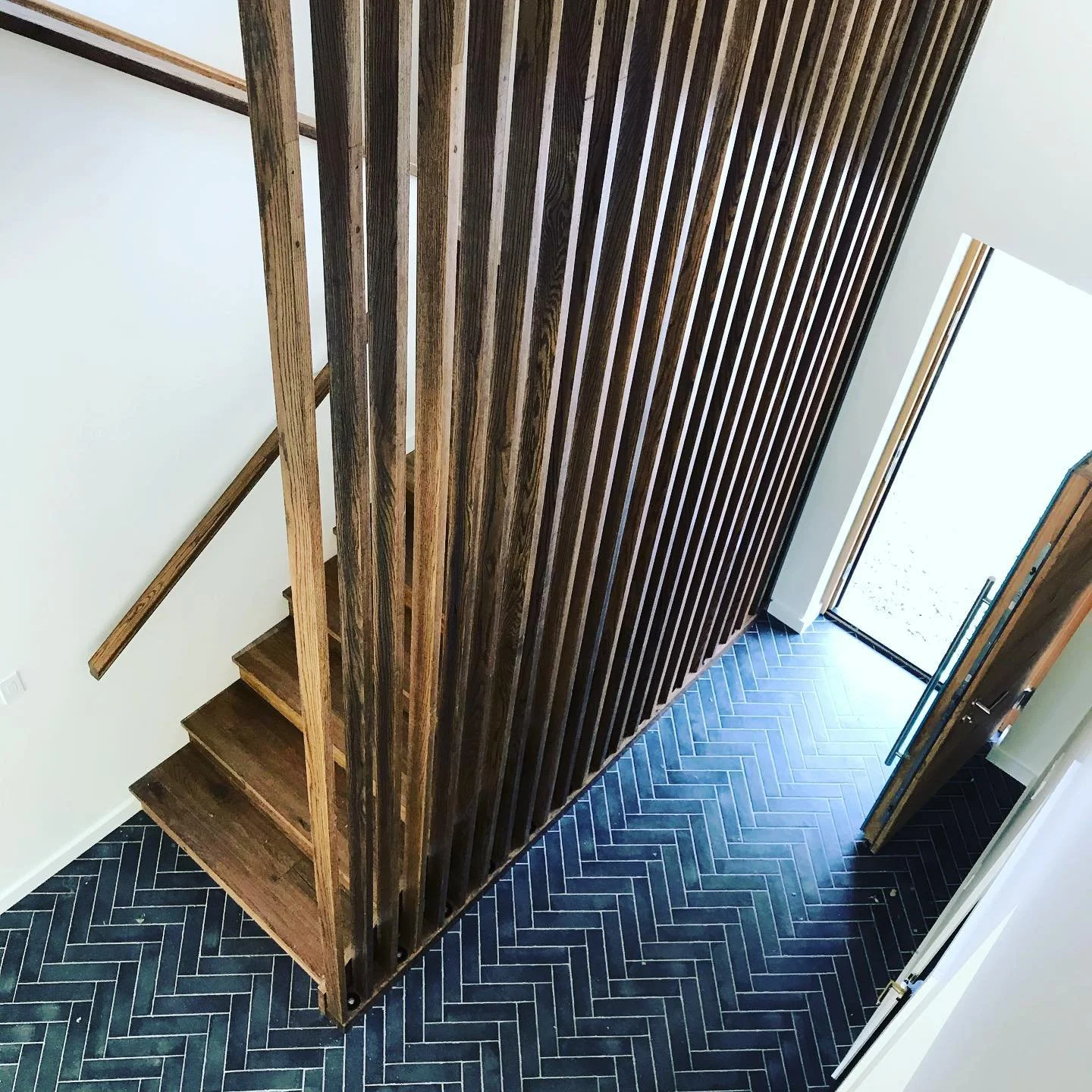 wooden railing staircase in a modern house with black floor tiles made by custom carpenter in Squamish