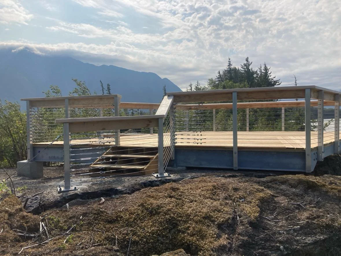 outdoor wood deck with a custom handrail with luxurious high quality material standing in front of a nice sunny day in Whistler