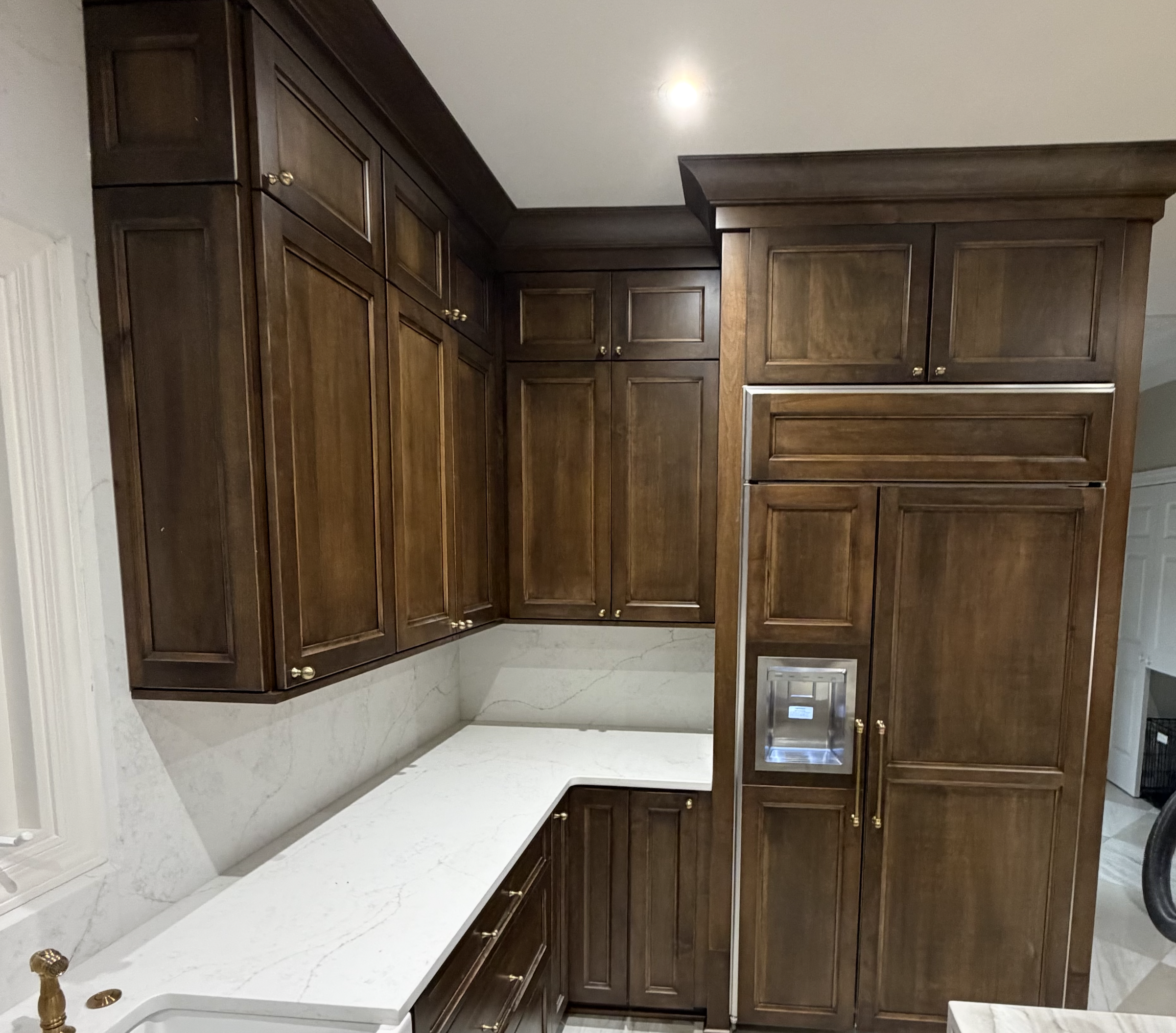 Kitchen with dark wood cabinets and white marble countertops.