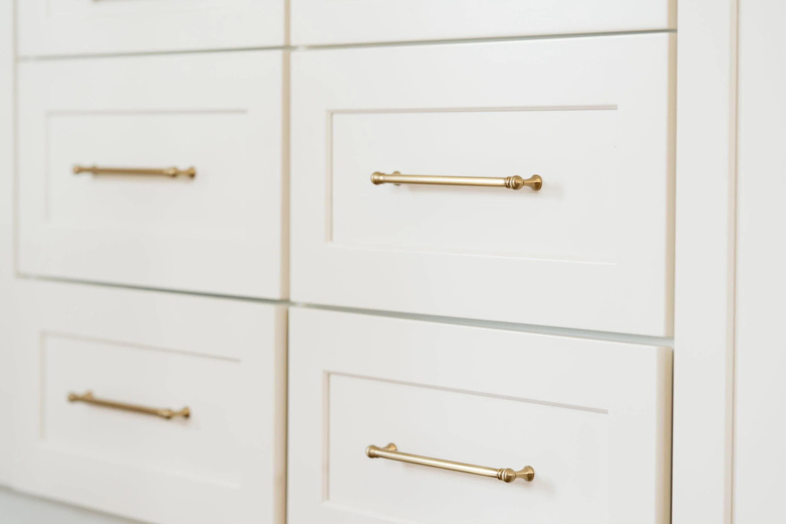 Close-up of white drawers with gold handles.