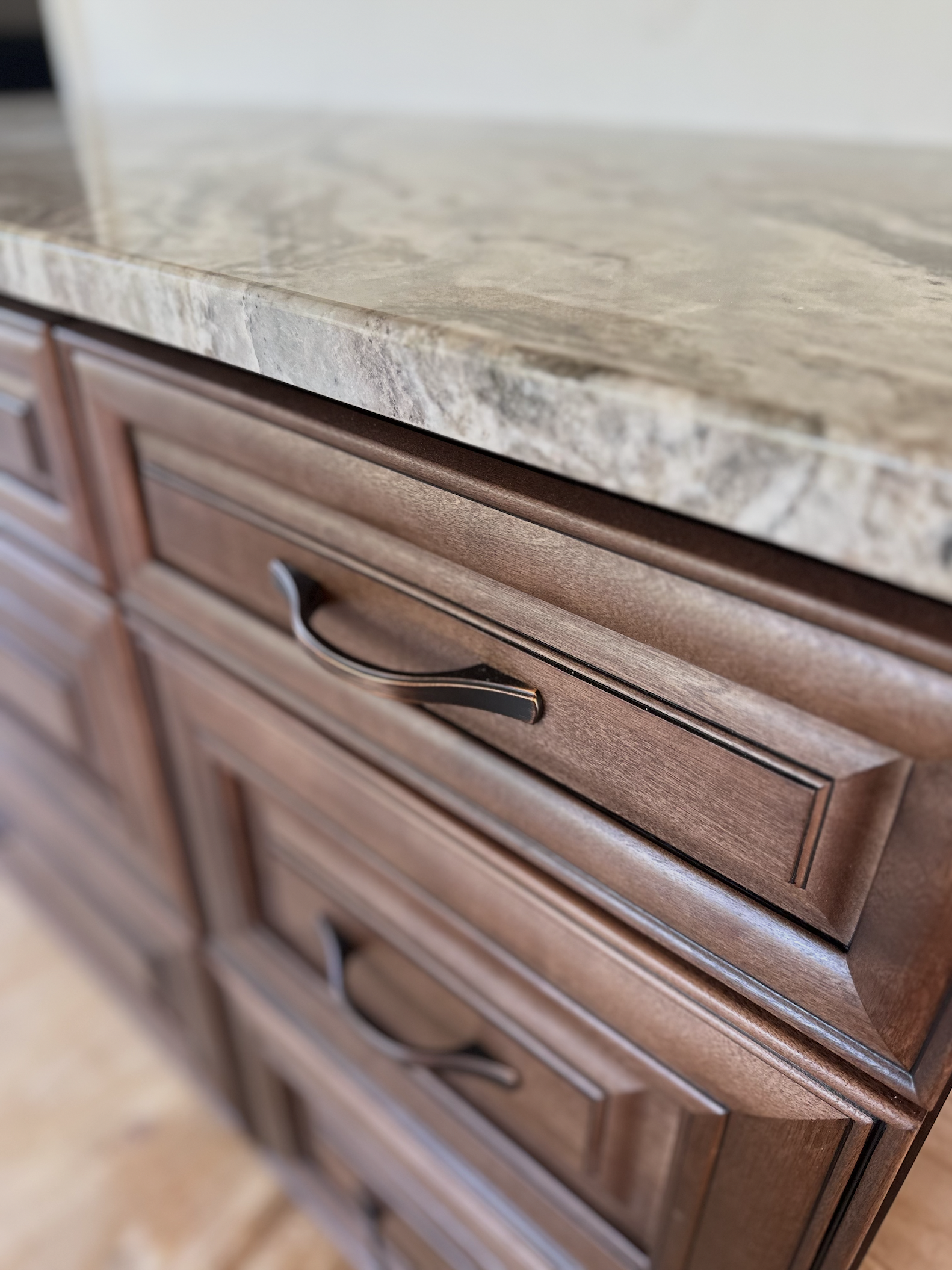 Close-up of wooden kitchen cabinets with a marble countertop.