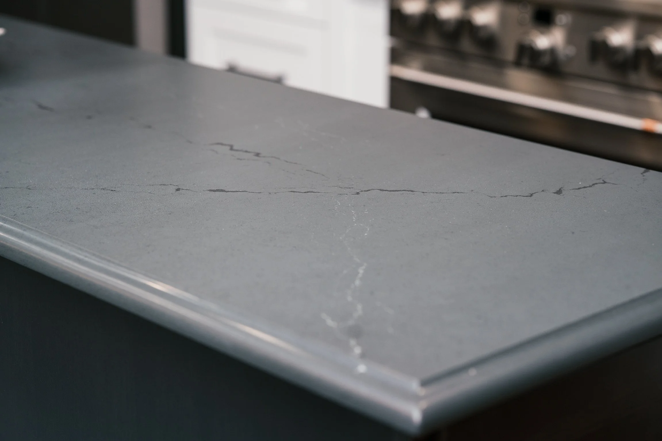 Close-up of a grey marble countertop with visible cracks.