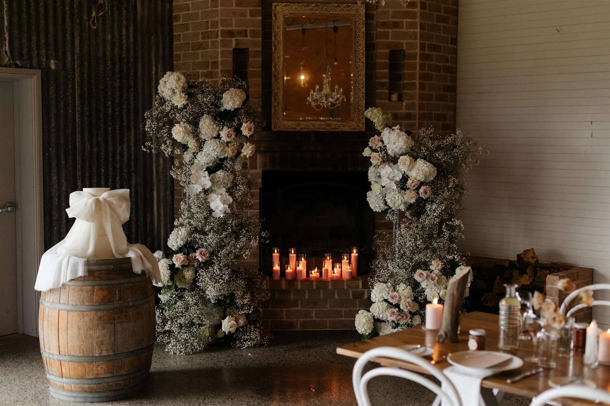 Wedding decoration scene with candles, flowers, and a barrel.