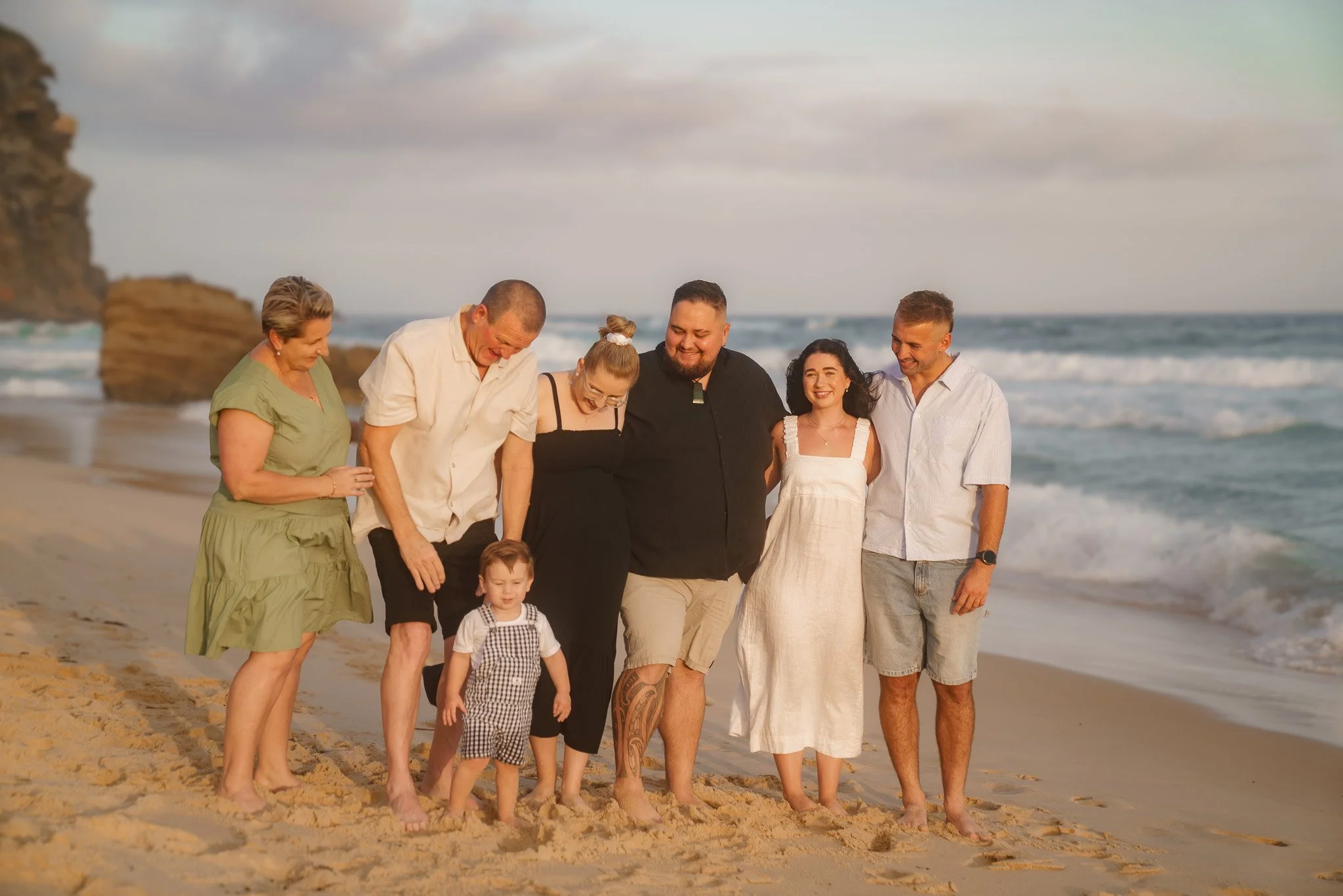 Family walking together on the beach during sunset, enjoying the ocean view and smiling.