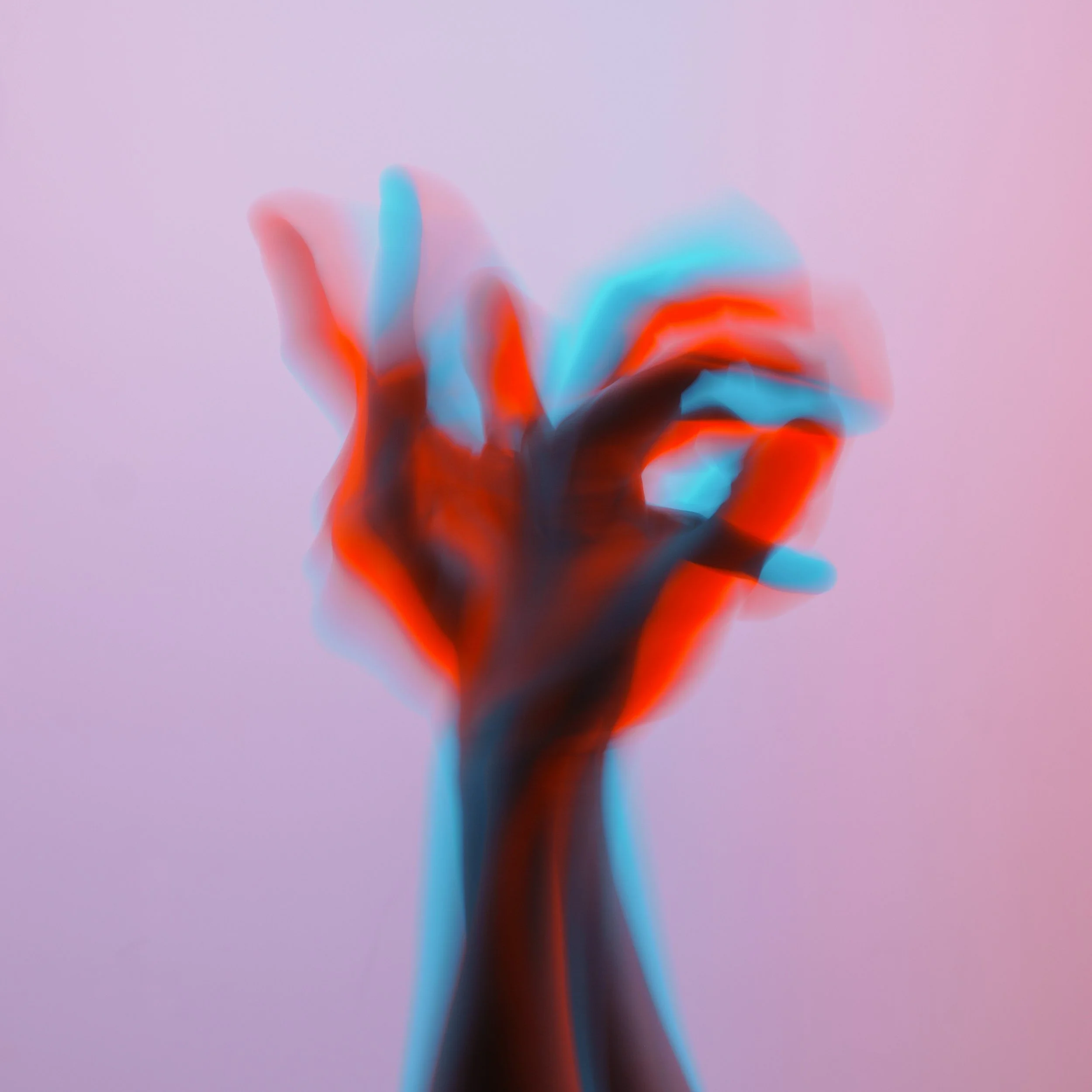 Blurred image of two hands crossed with fingers spread and reaching upward with red and blue tint and a lavender background